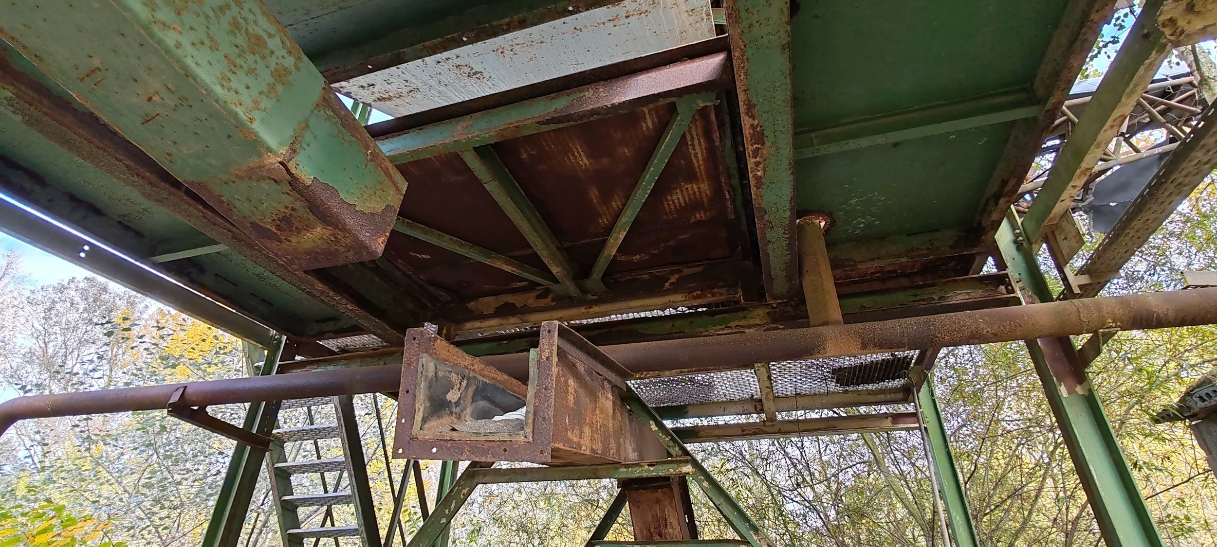 Verrosteter, grüner Metalldachturm im Freien, umliegende Bäume, Blick nach oben.