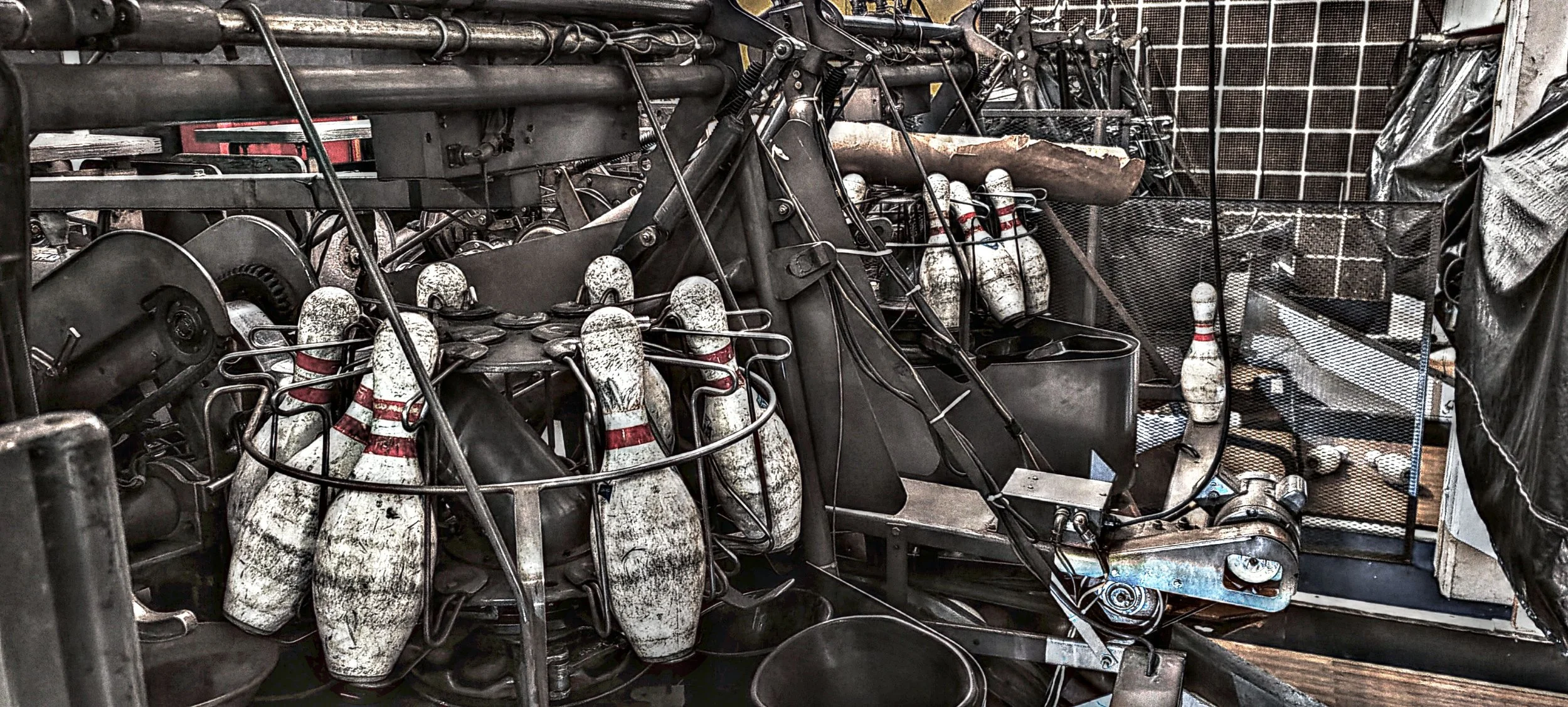 Eine alte, verrostete Bowlingbahn mit mehreren Bowlingkugeln und Pins.