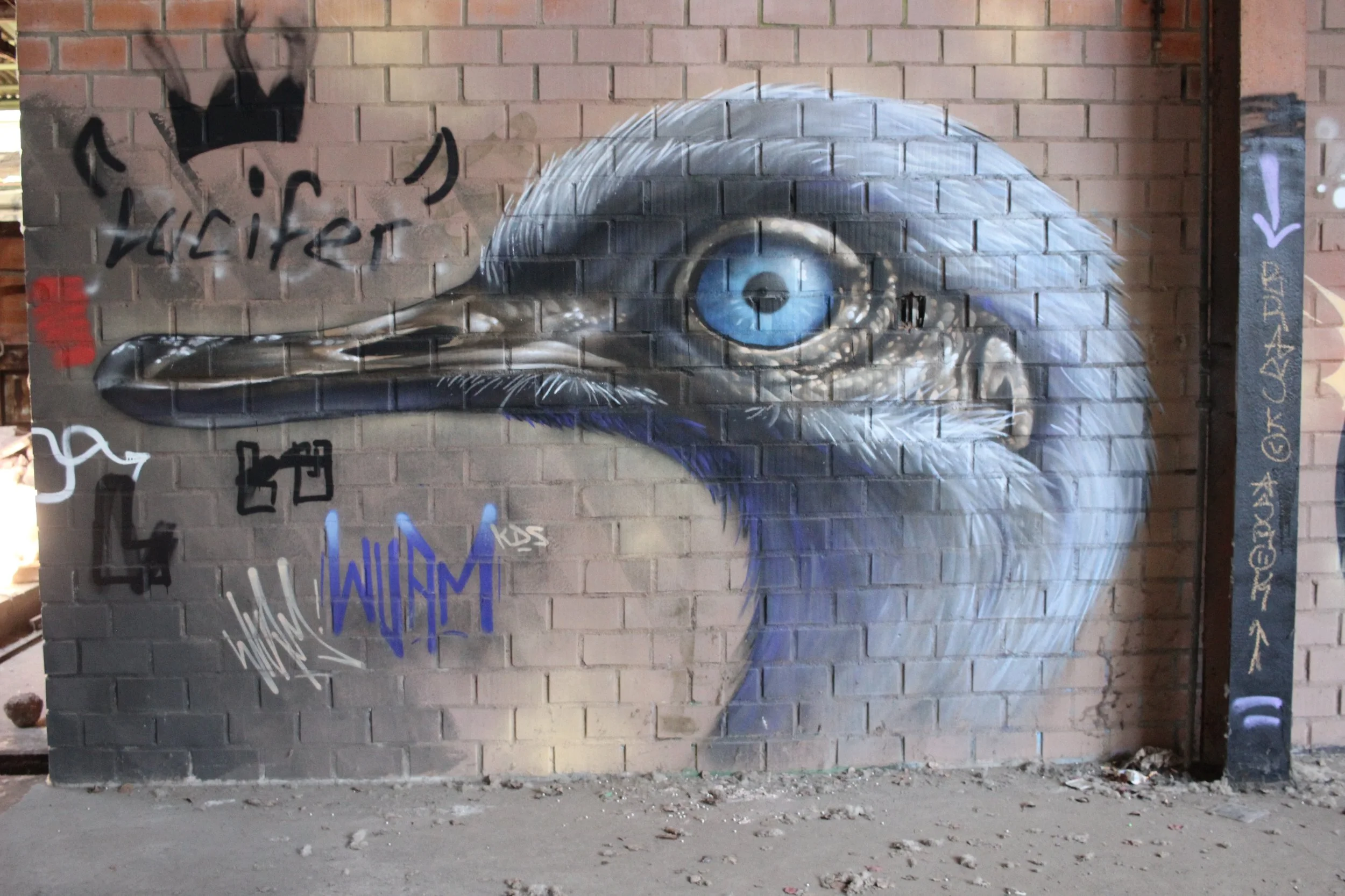 Graffiti-Kunstwerk eines Reiher auf einer Backsteinmauer, mit blauer Auge, schwarzen Schnabel und weißem Gefieder