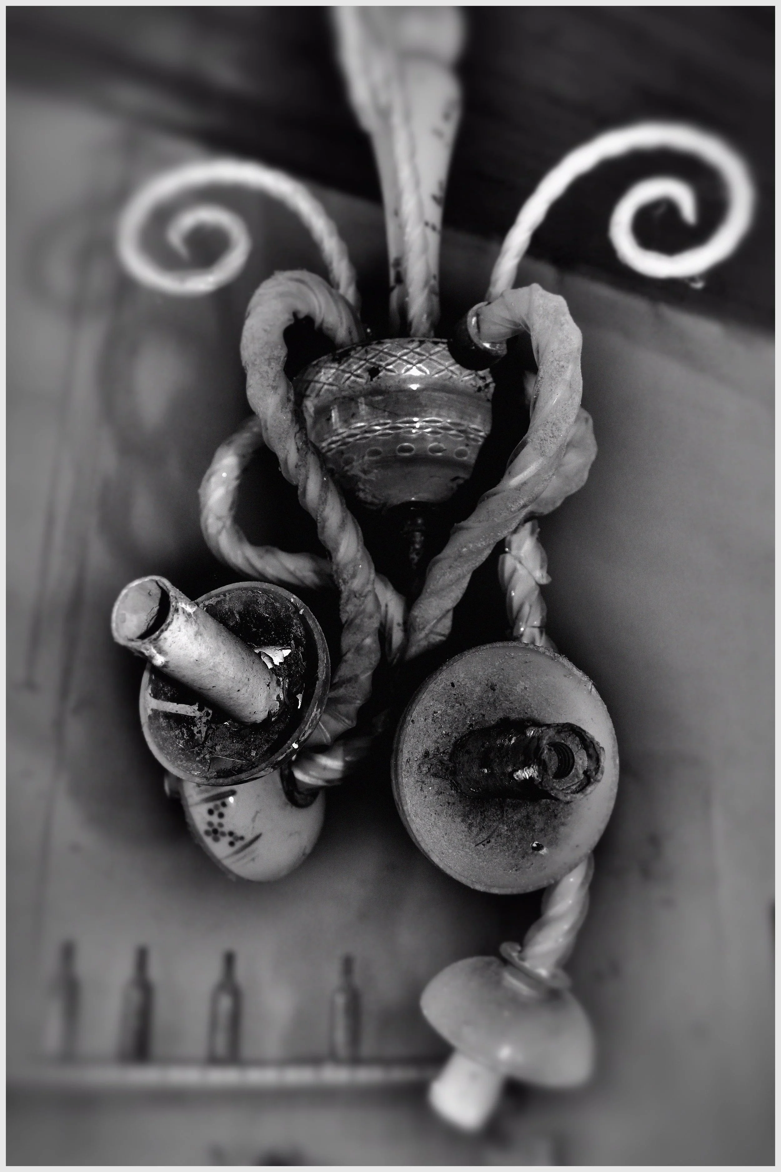 Schwarz-Weiß-Foto von verschiedenen Kerzen, einem Schneemann, einem Herz und einer Feder auf einer Tischplatte, aufgenommen aus der Vogelperspektive.