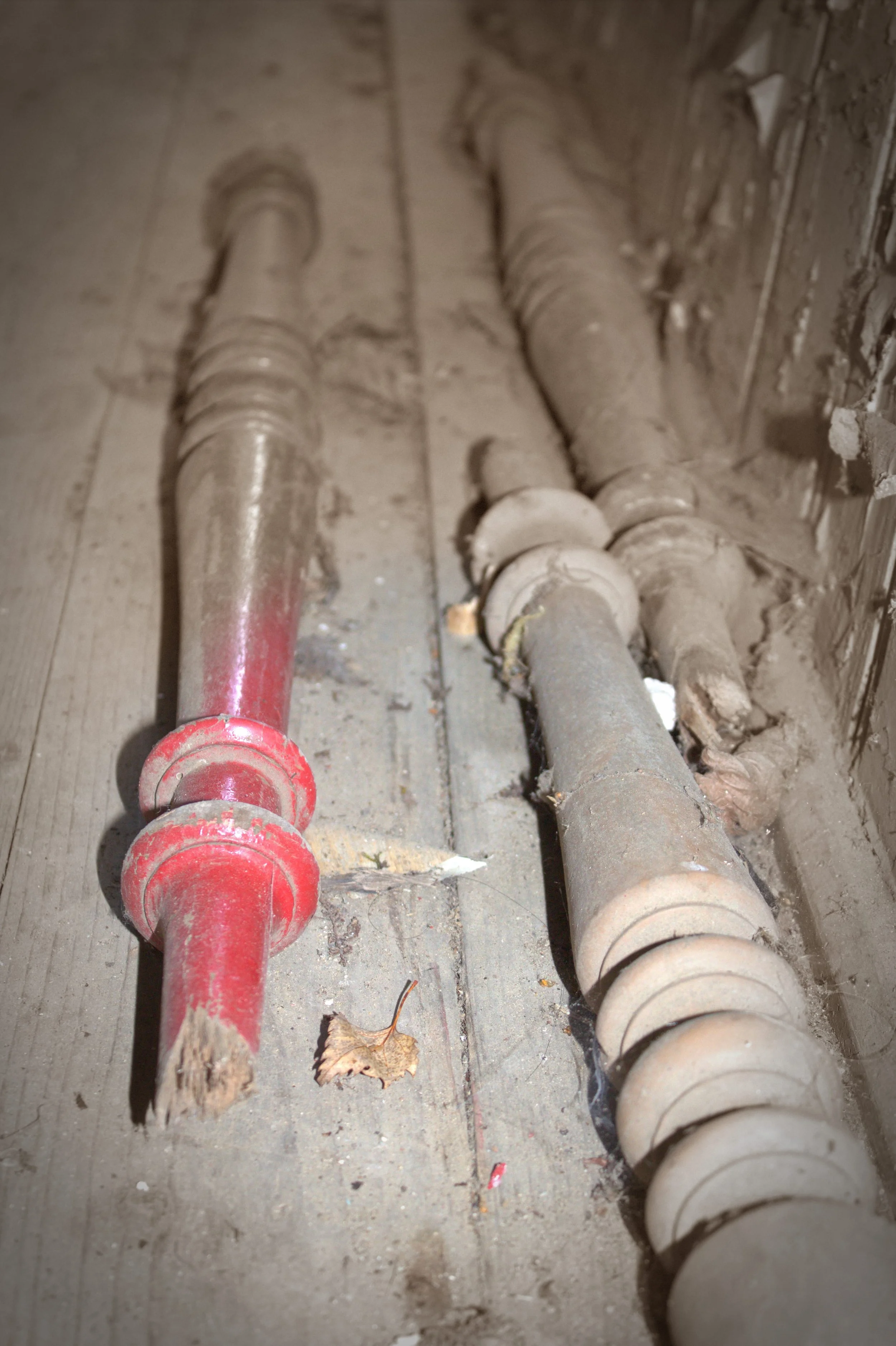 Drei alte, staubige Rohrleitungen auf einem Boden, eine rote und zwei graue, in einer Baumarktsituation oder Baustelle.