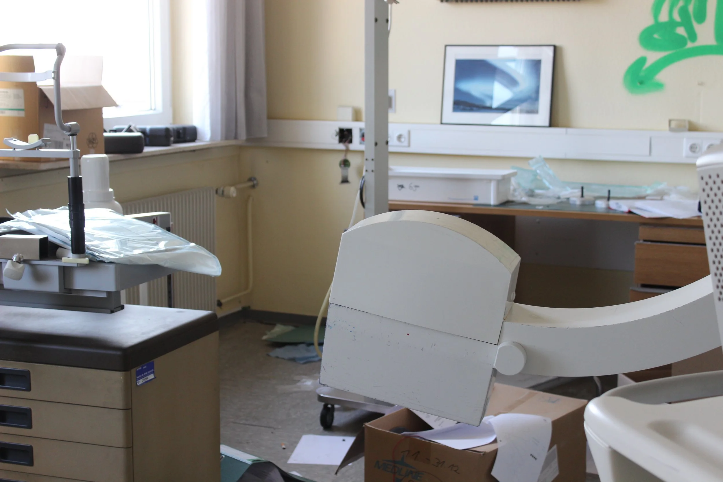 Ein unordentlicher Raum in einem Krankenhaus mit medizinischem Equipment, Papieren und leeren Kartons.
