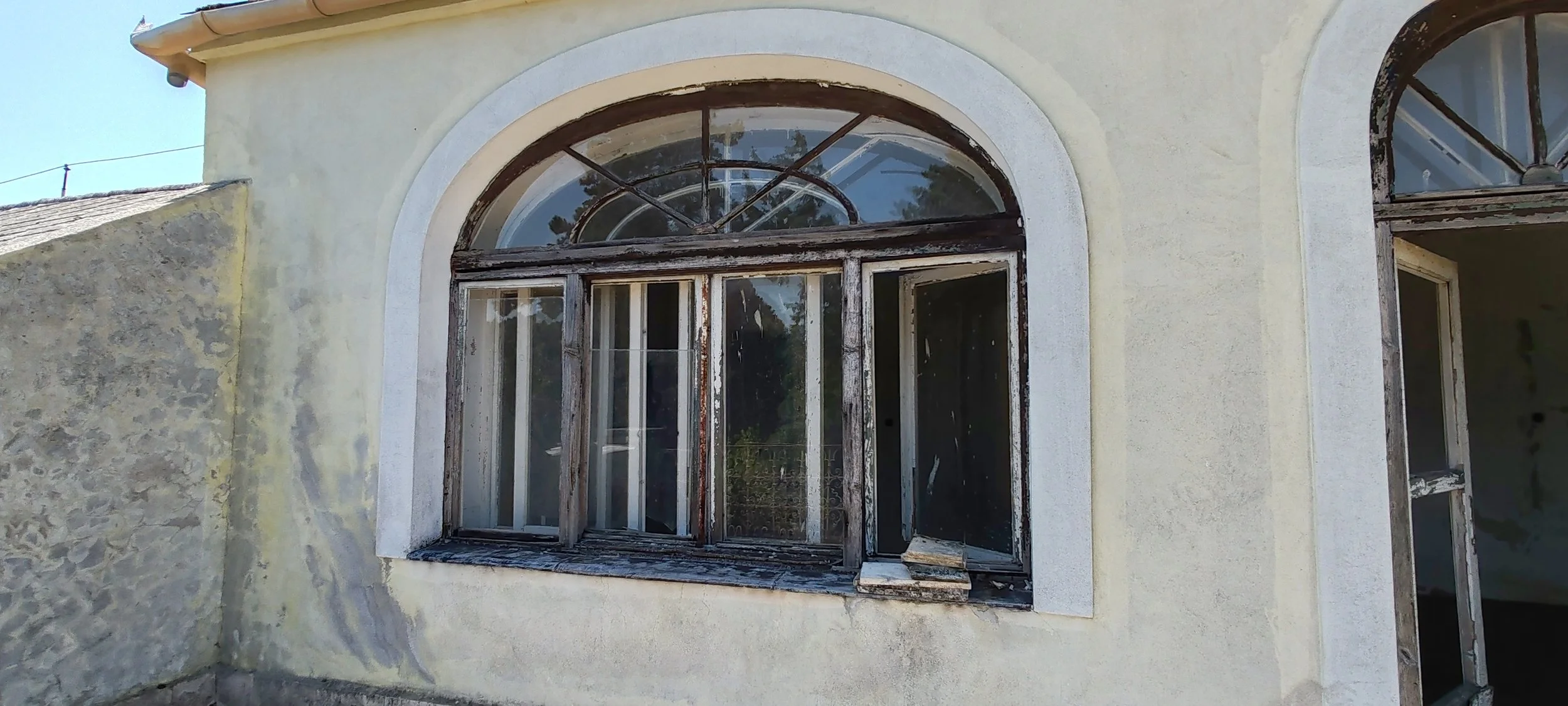 Verwittertes Fenster an einer alten, gelben Wand eines Gebäudes