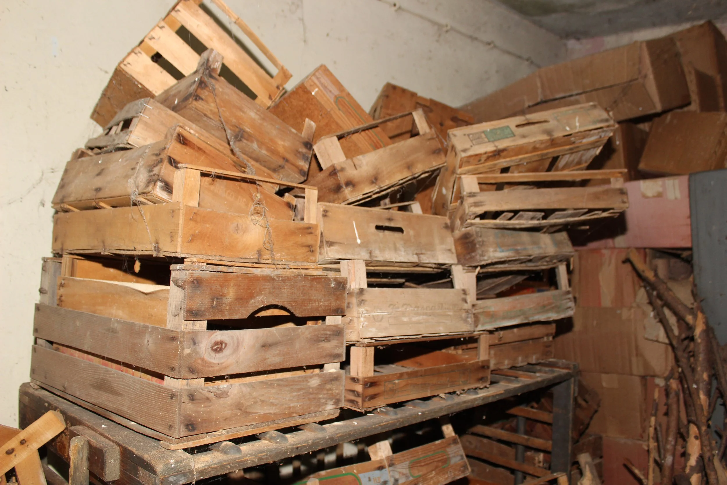 Haufen alter verstaubter Holzpaletten in einem Lagerraum mit Betonwänden.