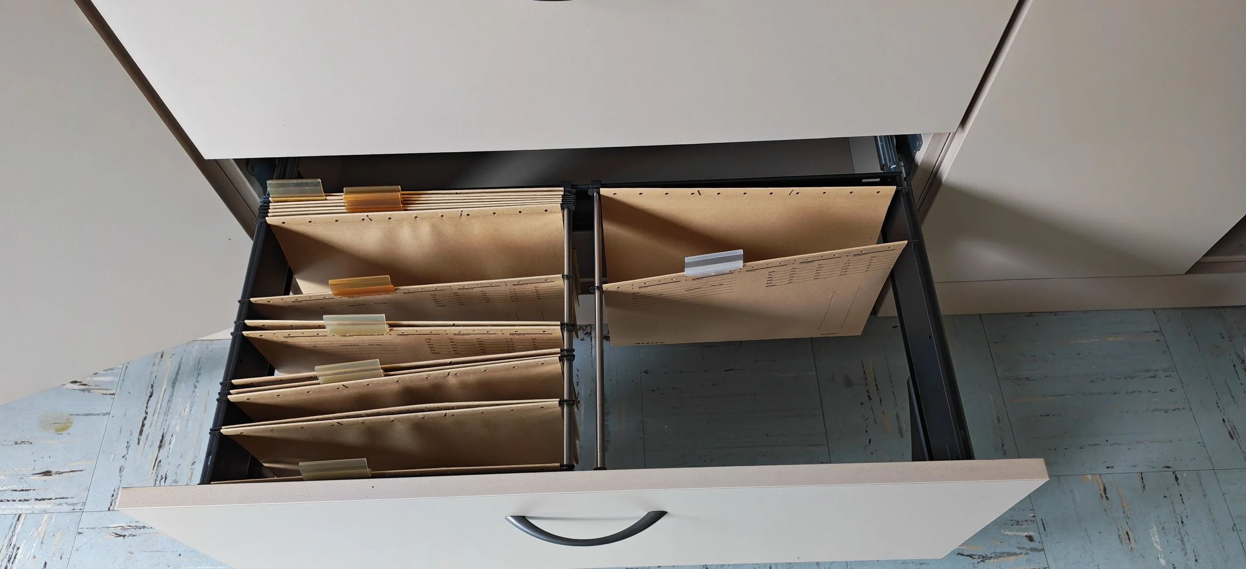 Offene Schublade mit mehreren beige Aktenordnern und Ablagefächern in einem Büro