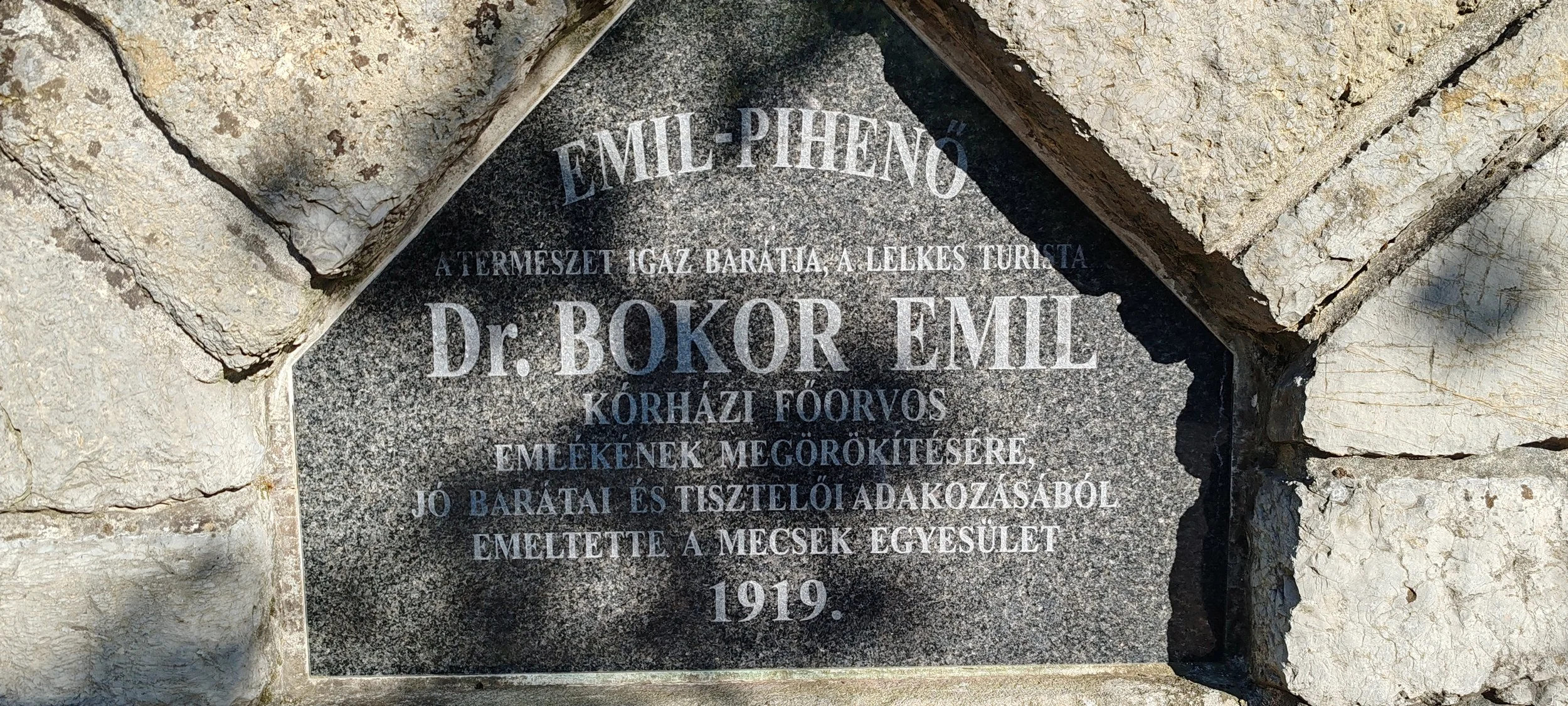 Gedenkstein für Dr. Bokor Emil, 1919, in eine Steinmauer eingelassen, mit eingravierter Beschriftung in ungarischer Sprache.