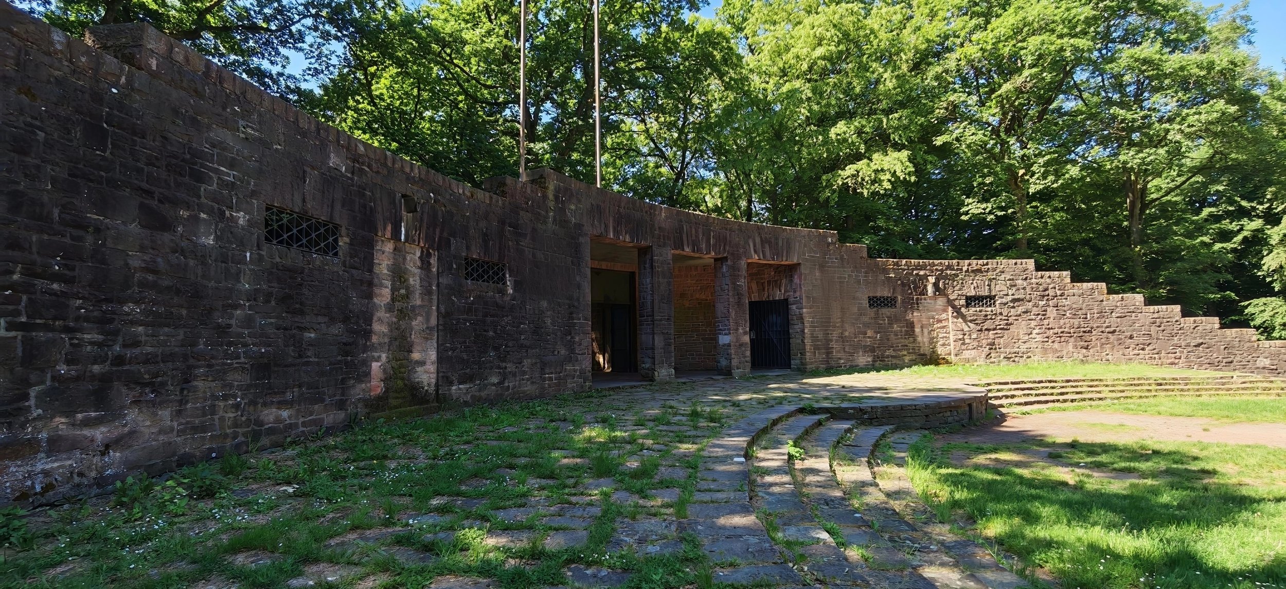 Alter Steintheater im Grünen bei Tageslicht, mit Stufen und Eingängen.