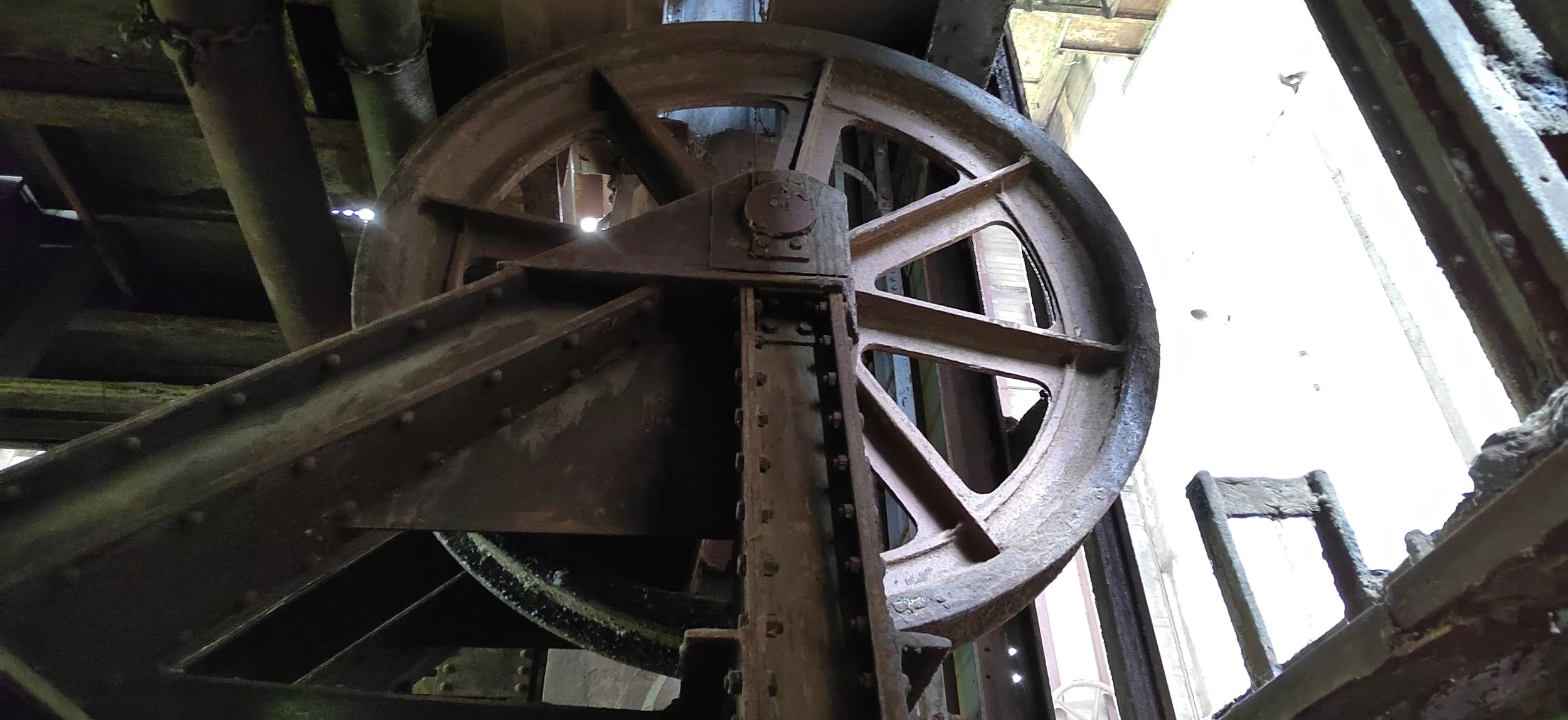 Ein großes, altes Zahnradrad aus Metall in einer industriellen Umgebung.