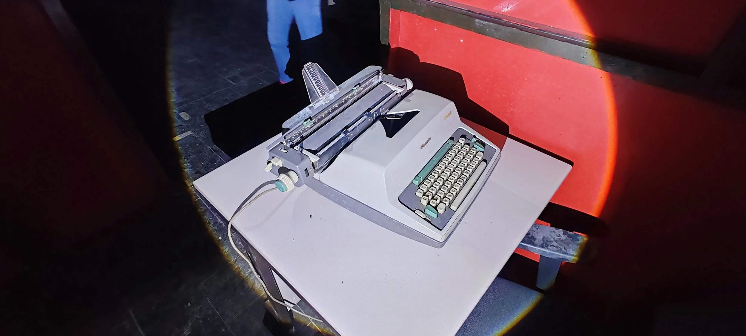 Alter elektrische Schreibmaschine auf einem Tisch in einem dunklen Raum.