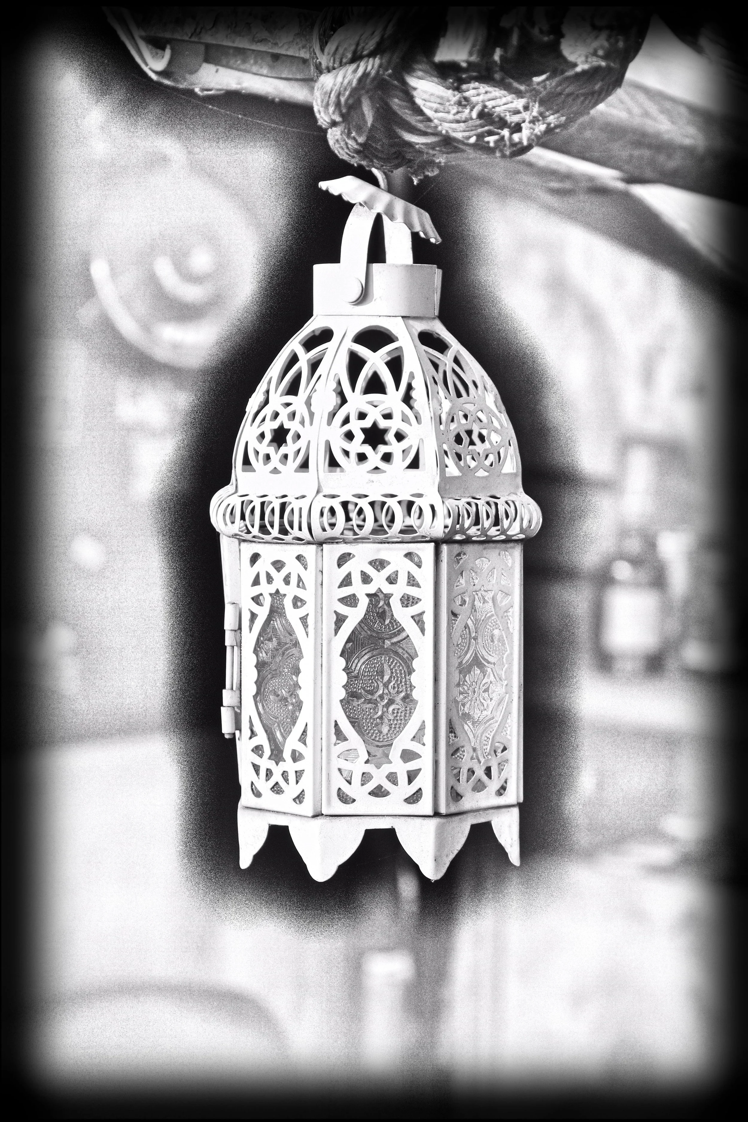 Ein dekoratives, weißes, metallisches Laternen-Design mit filigranen Mustern, aufgehängt an einem Ort, möglicherweise für eine kulturelle oder festliche Dekoration.