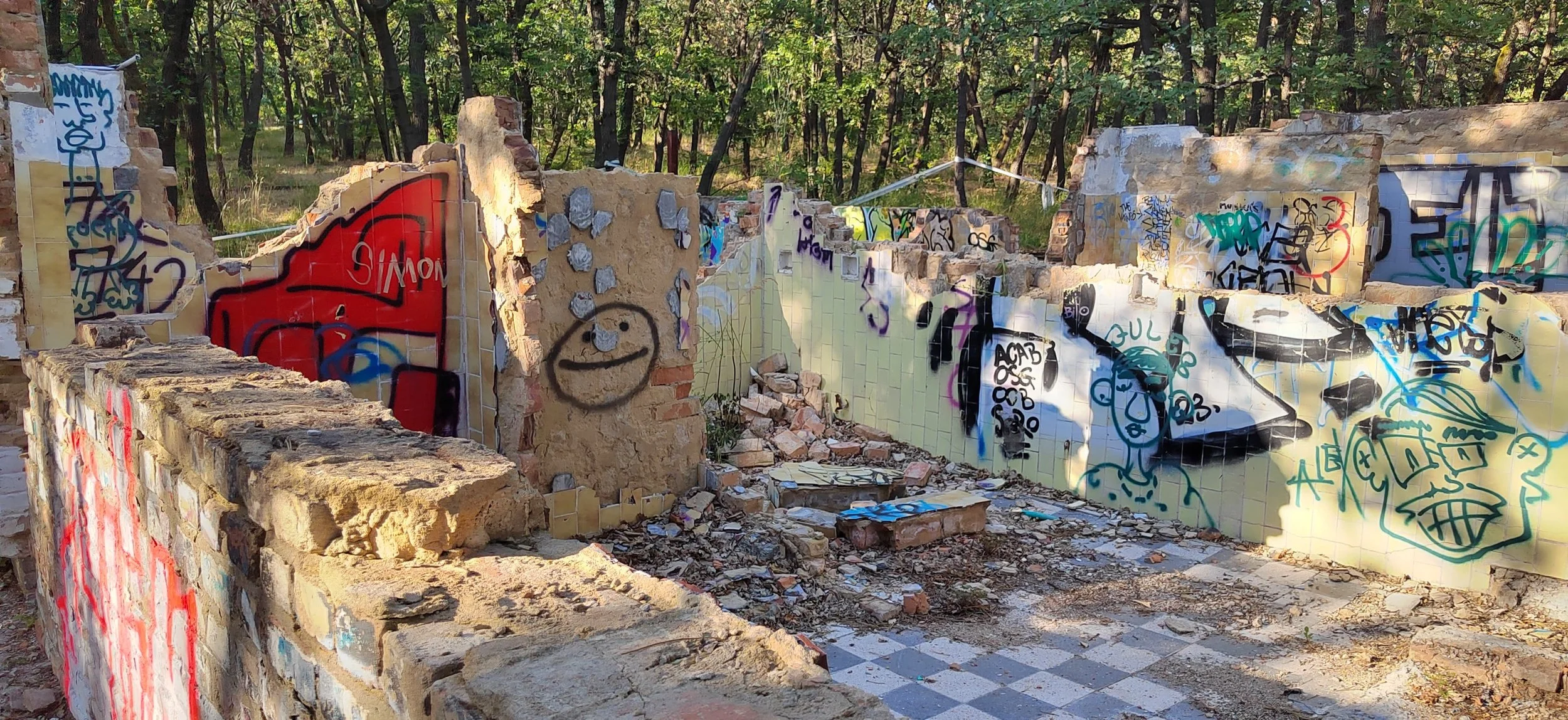 Vergessene und mit Graffiti bedeckte Überreste einer verlassenen Struktur in einem Wald.