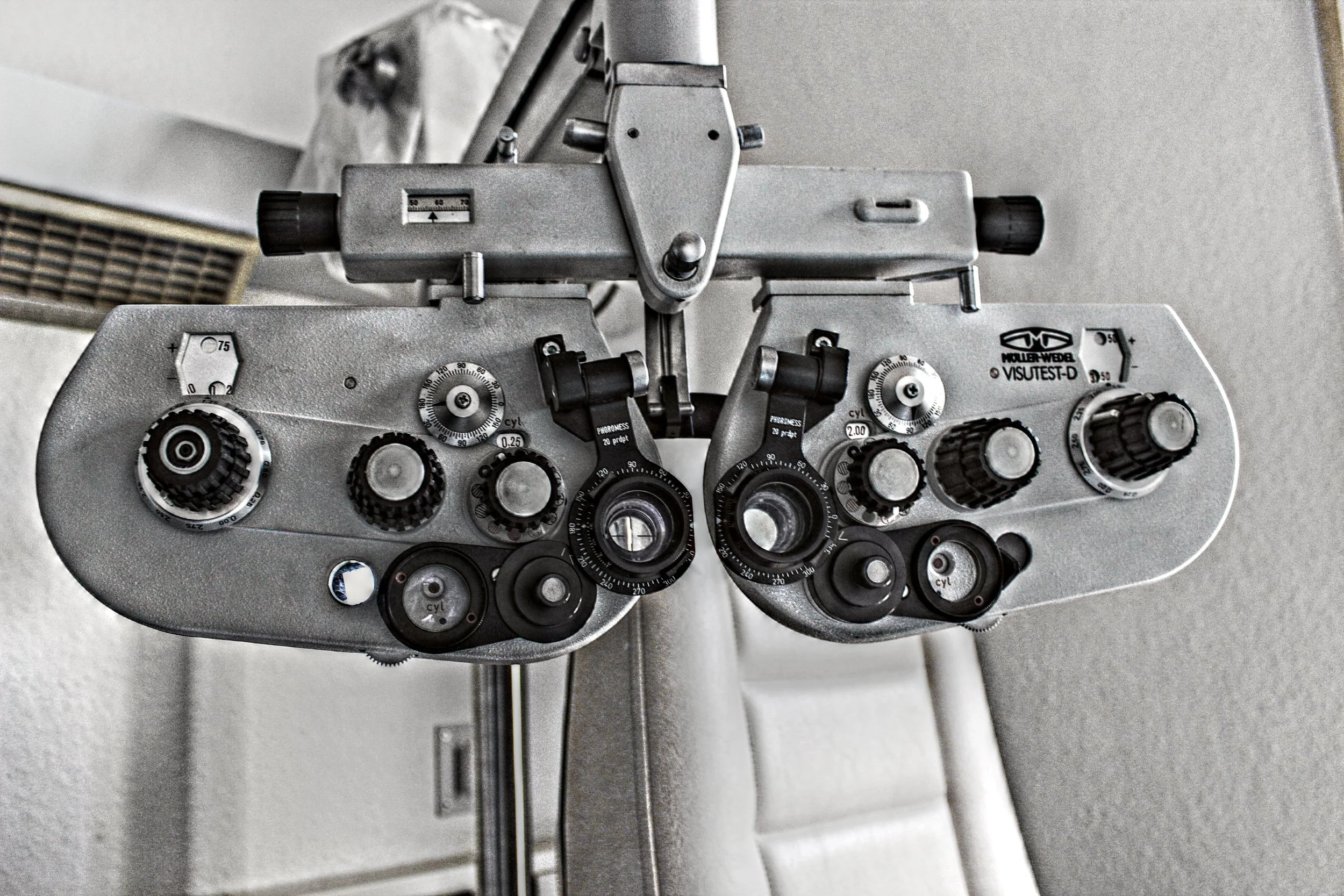 Augensessel mit verstellbaren Linsen, Drehknöpfen und Messskalen für Augenuntersuchungen.