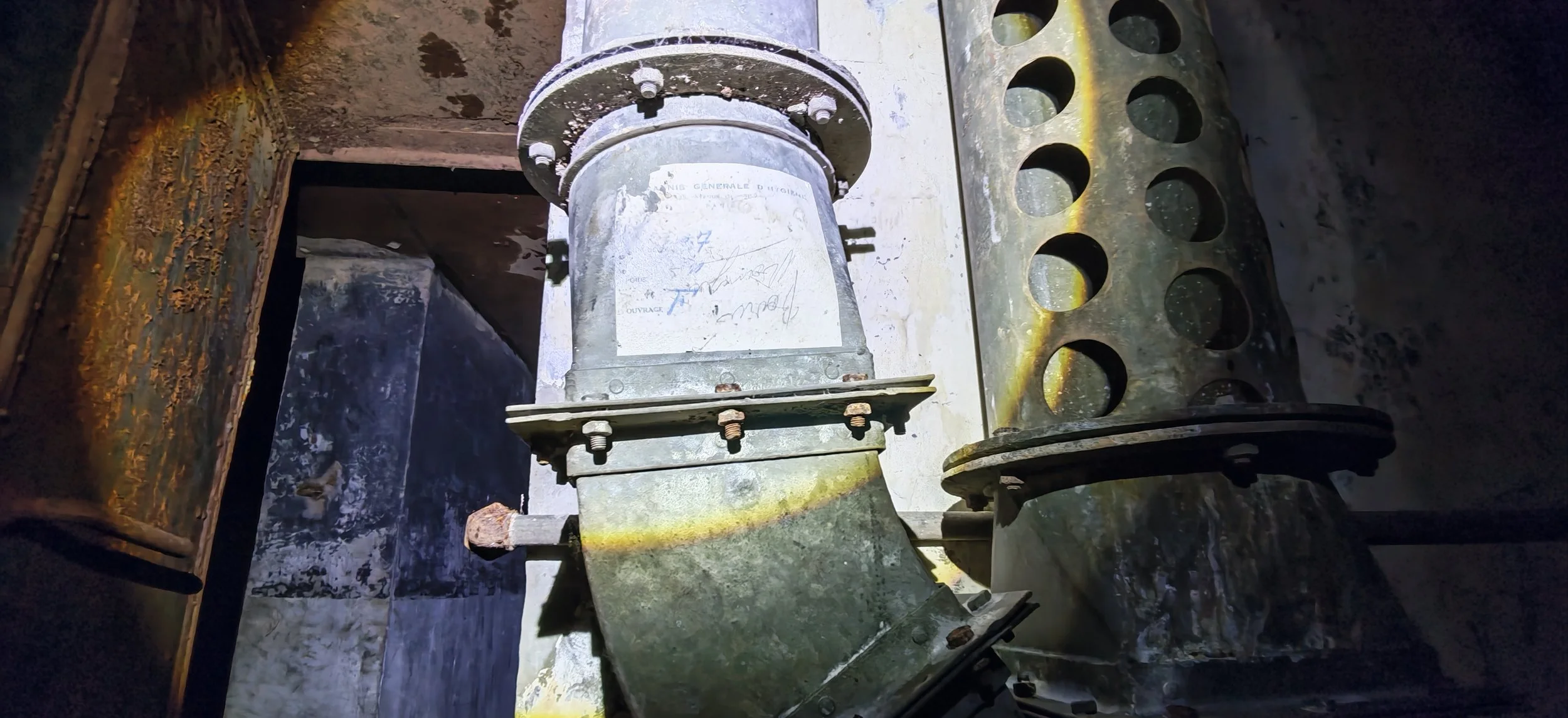 Ein industrielles Maschinenteil, vermutlich eine elektrischen Motor oder Antriebskomponente, montiert auf einer Metallbasis, in einer dunklen, verrauchten Umgebung.