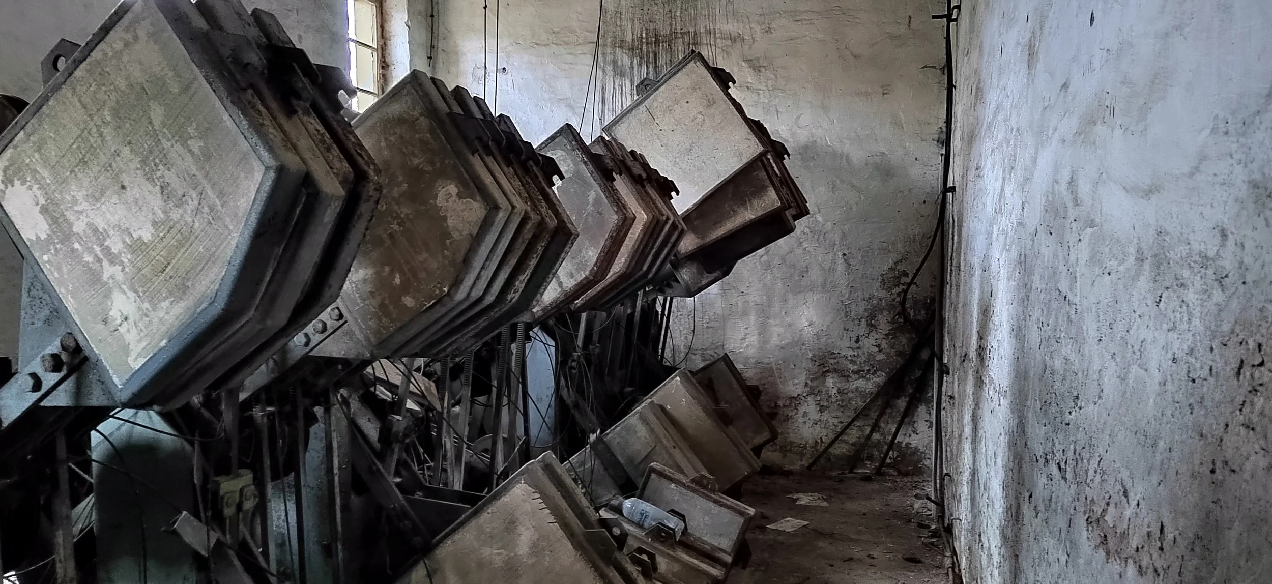 Verstaubte und defekte Leuchtstofflampen hängen an einer unordentlichen, schmutzigen Wand in einem alten, verlassenen Raum.