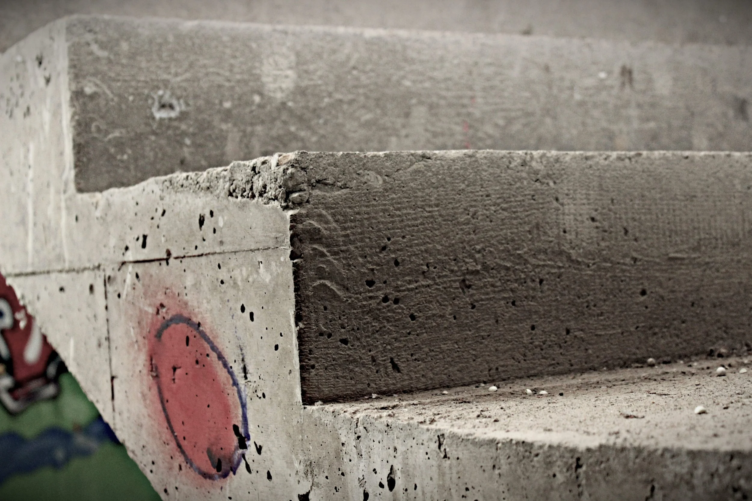 Nahaufnahme von Betonstufen mit grauer und heller Farbe, einige Graffiti sind sichtbar.