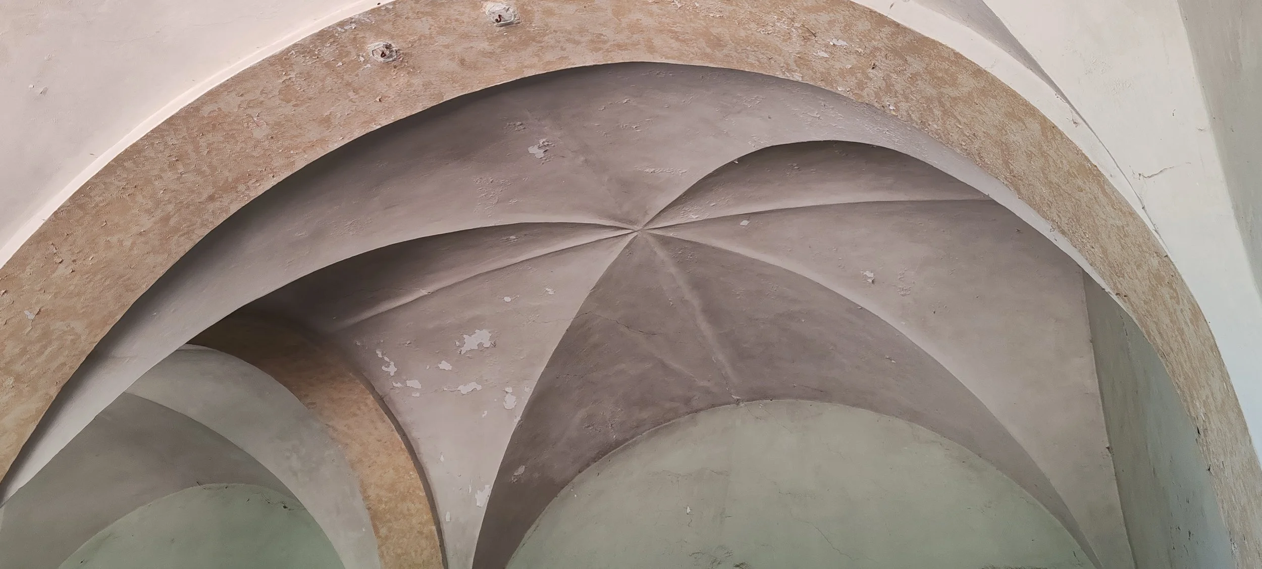 Architektur mit mehreren gewölbten Decken in unterschiedlichen Farben, some are beige and some are light green.