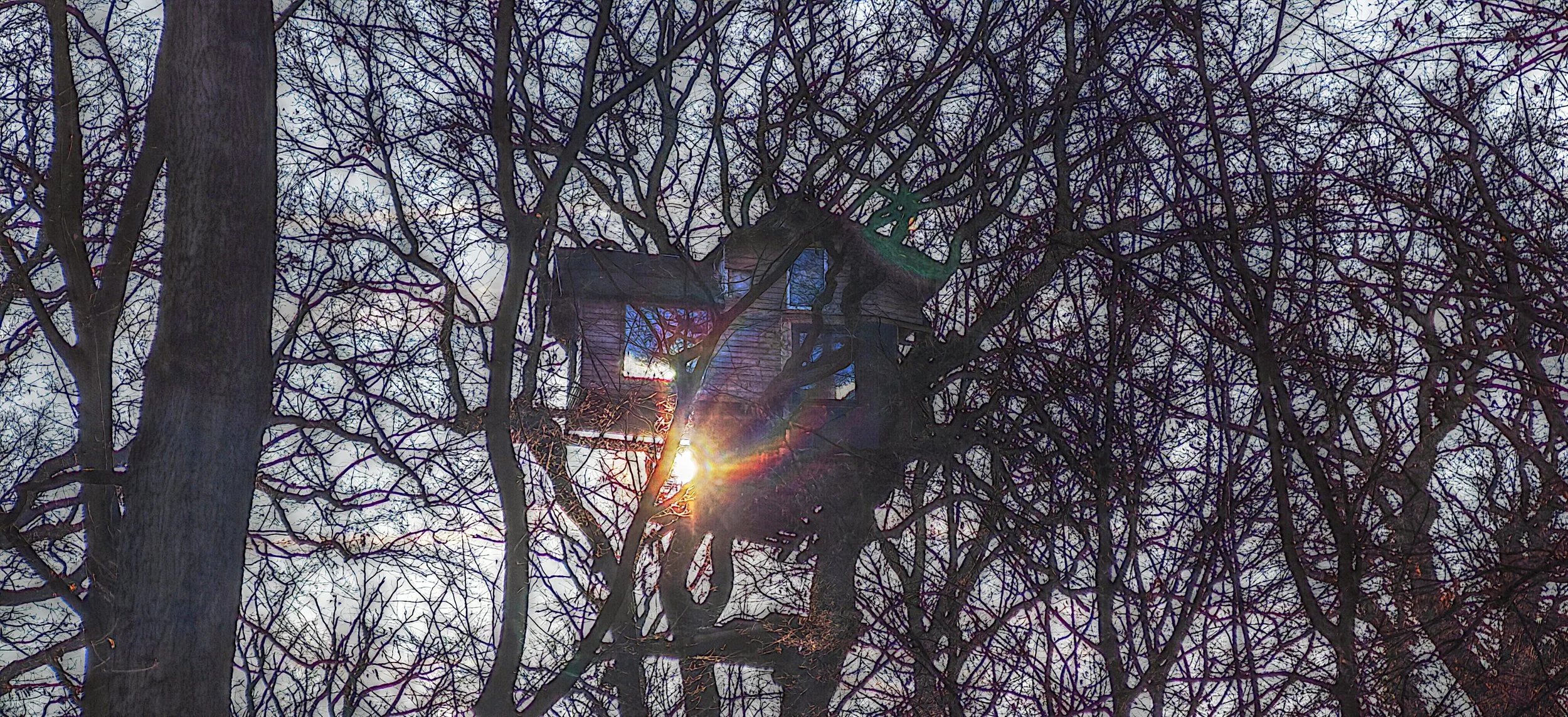 Ein Baumhaus ist in den Ästen eines Baumes, mit Sonnenlicht, das durch die Zweige scheint, bei Sonnenuntergang oder Sonnenaufgang.