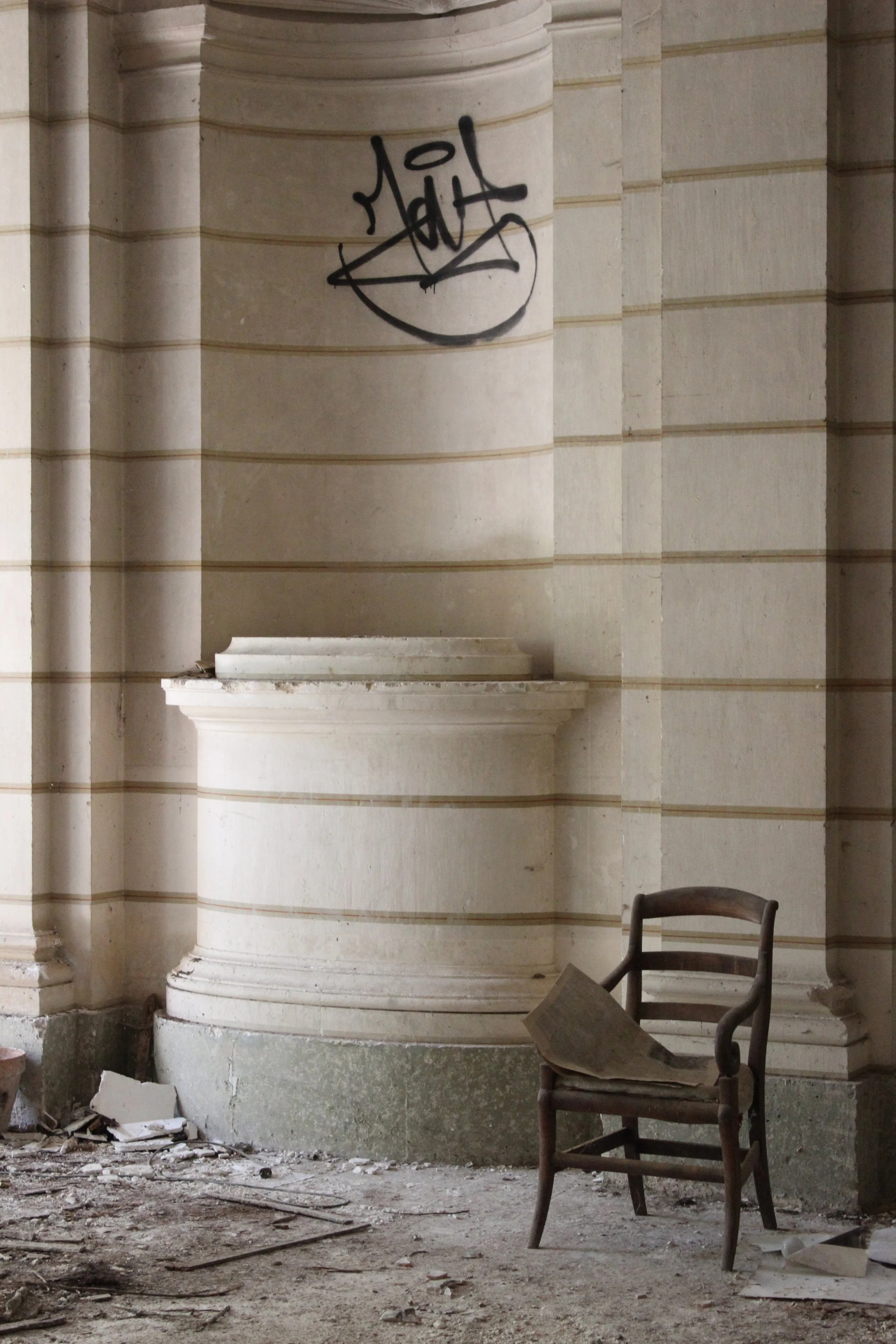 Verlassener Raum mit alten Möbeln und Graffiti an der Wand.