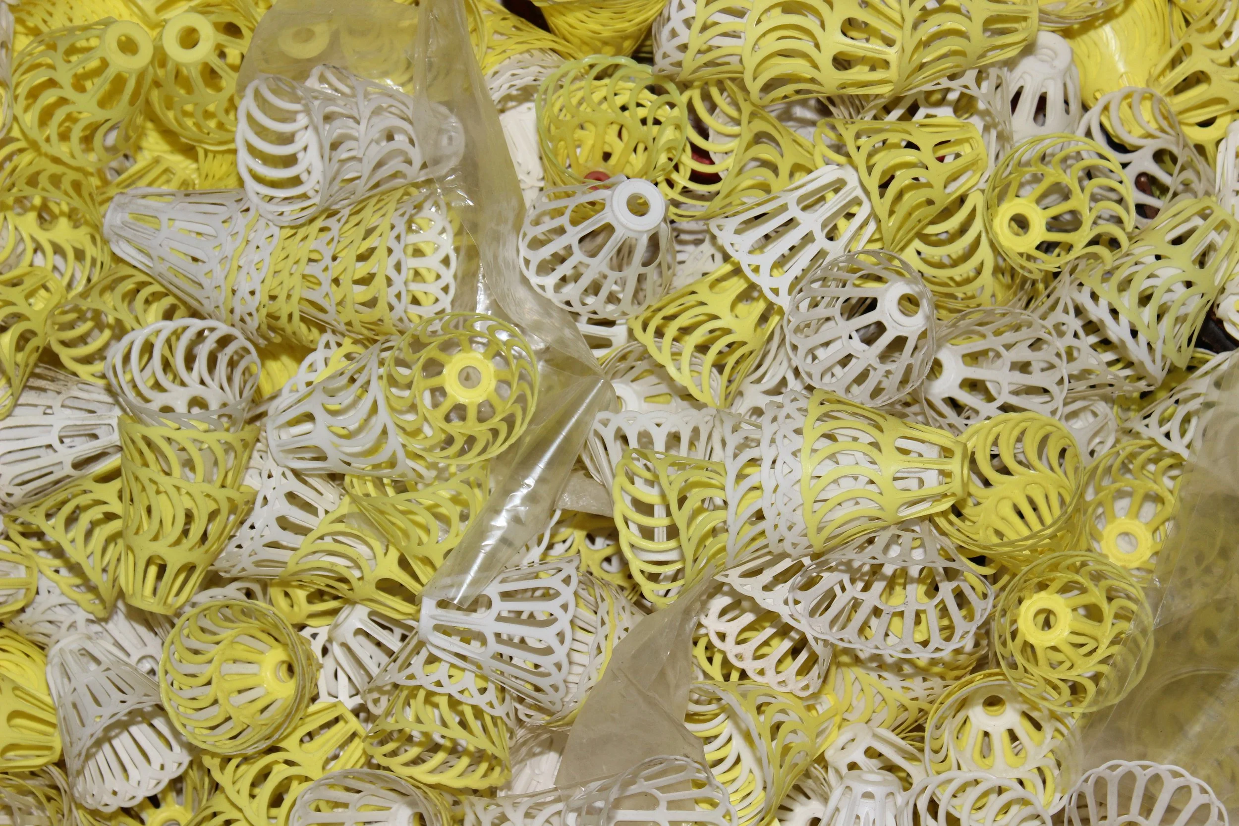 Eine große Menge gelber und weißer, strukturierter Einkaufskorb- und Flaschenschutzverschlüsse aus Kunststoff