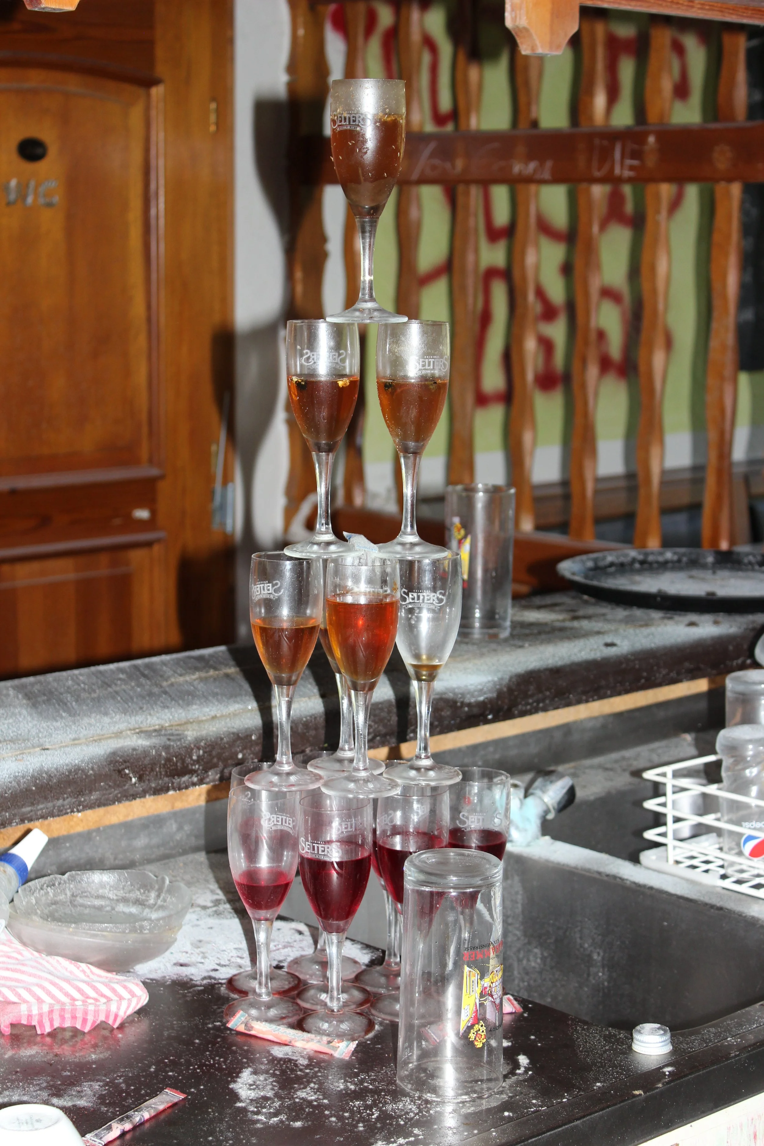 Ein Turm aus 10 gefüllten Weinkelchen, die auf einer Theke in einer Bar oder Kneipe stehen.