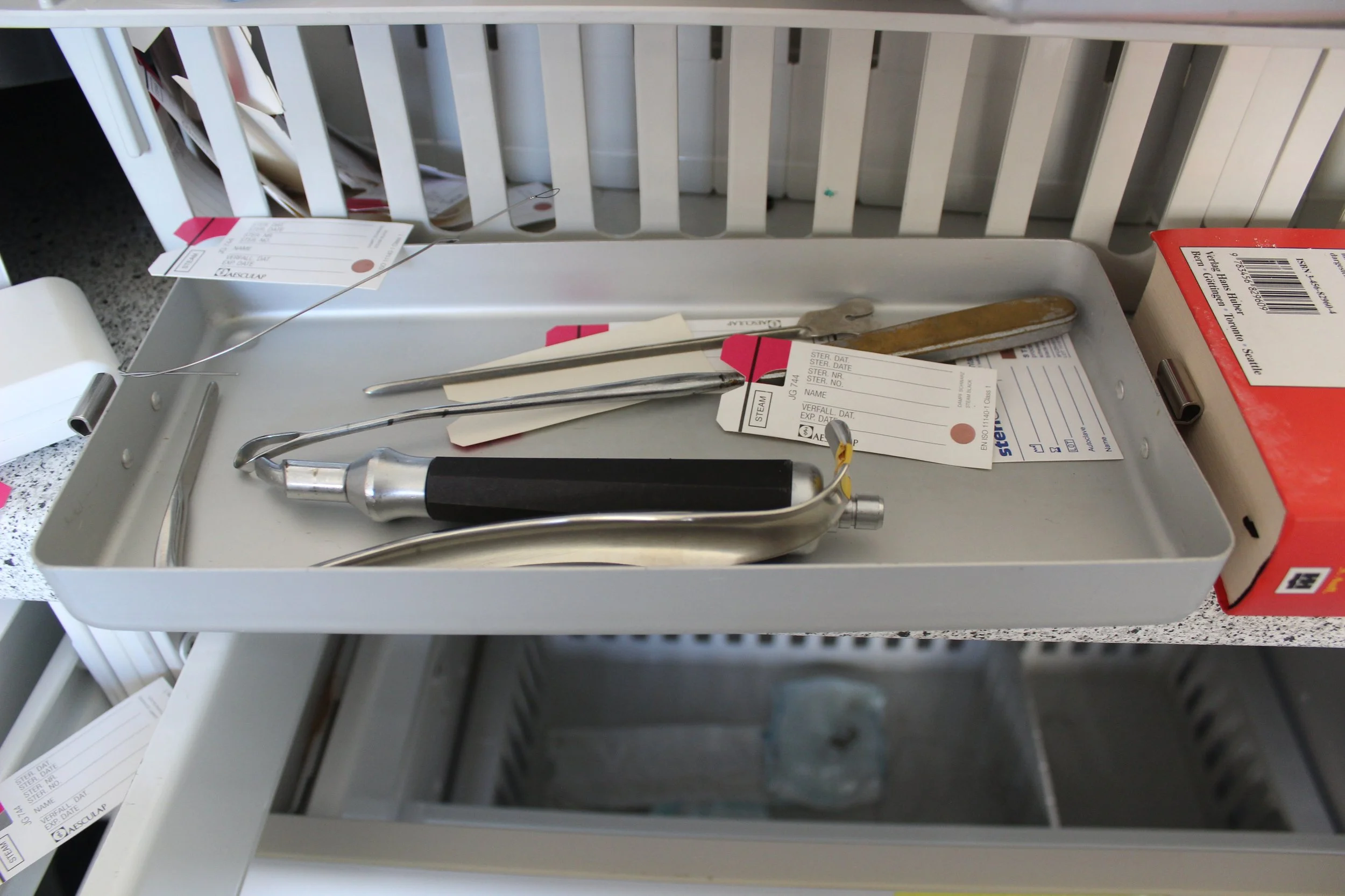 Medizinisches Instrumentarium auf einem Tablett in einer Klinik, inklusive Reflektor, chirurgische Instrumente und Anästhesie-Geräte.