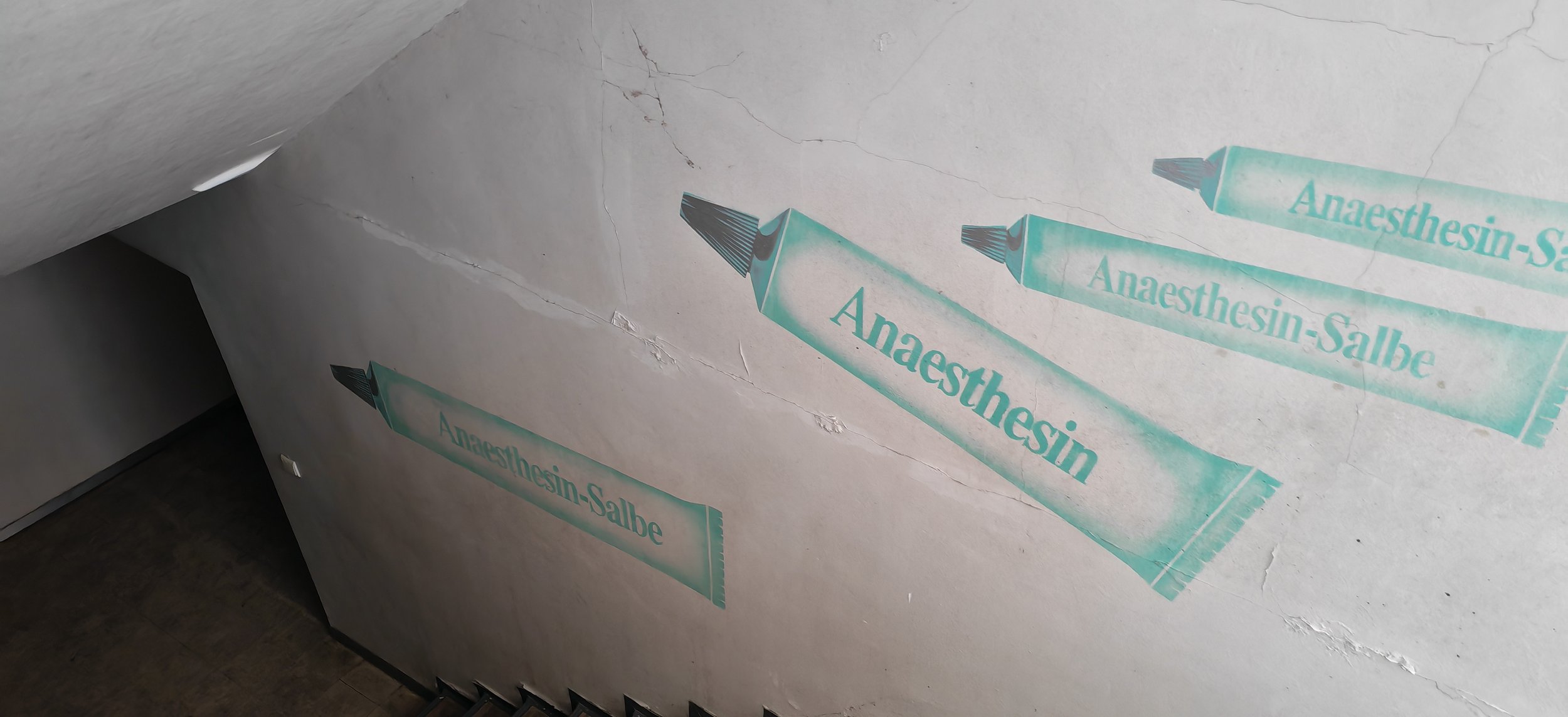 Wand mit Aufklebern, die den Namen "Anaesthesin" tragen, in einer medizinischen Einrichtung.