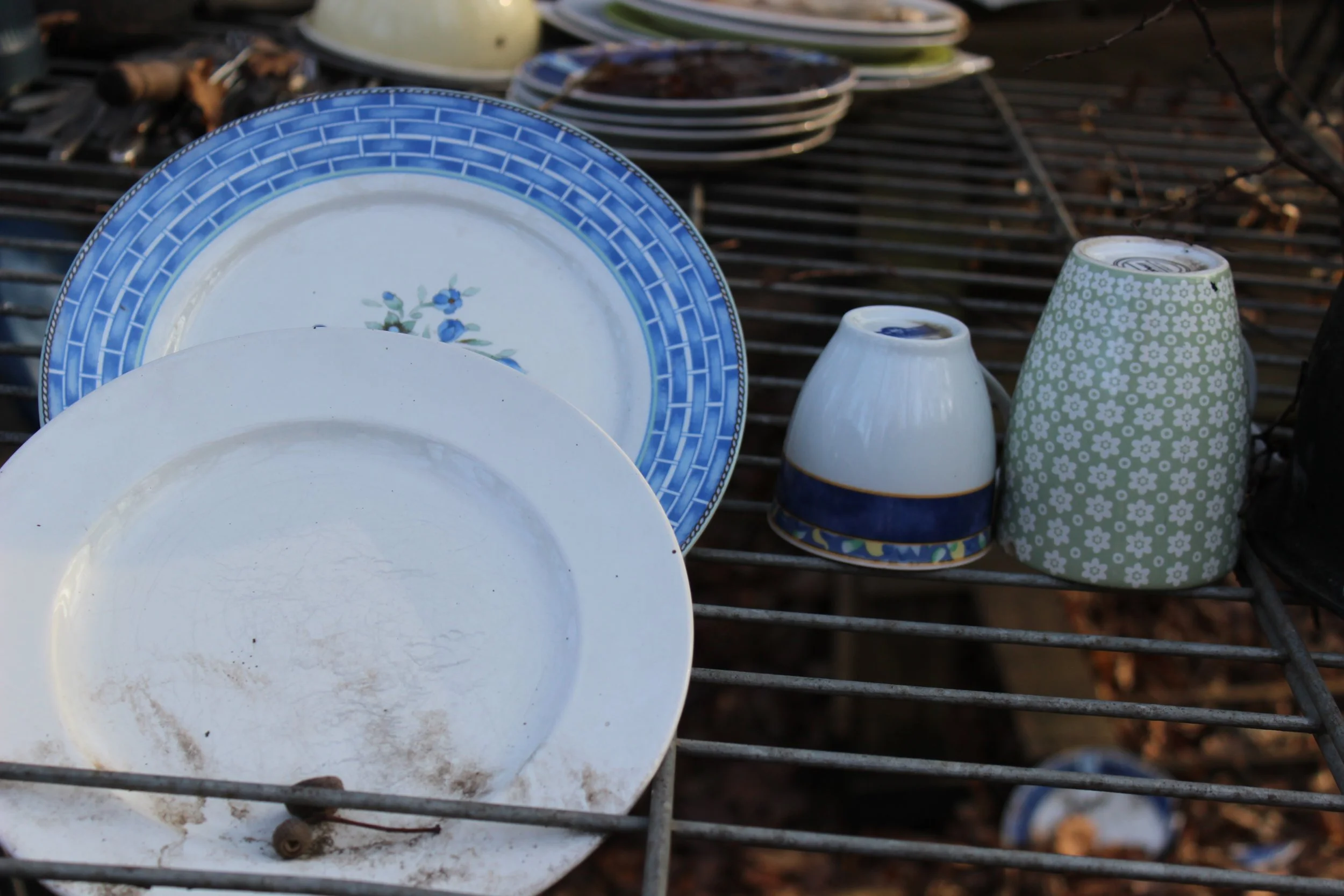 Teller, kleine Schüssel und Becher aus Geschirr mit blumen- und geometrischen Mustern, auf einem Grillrost