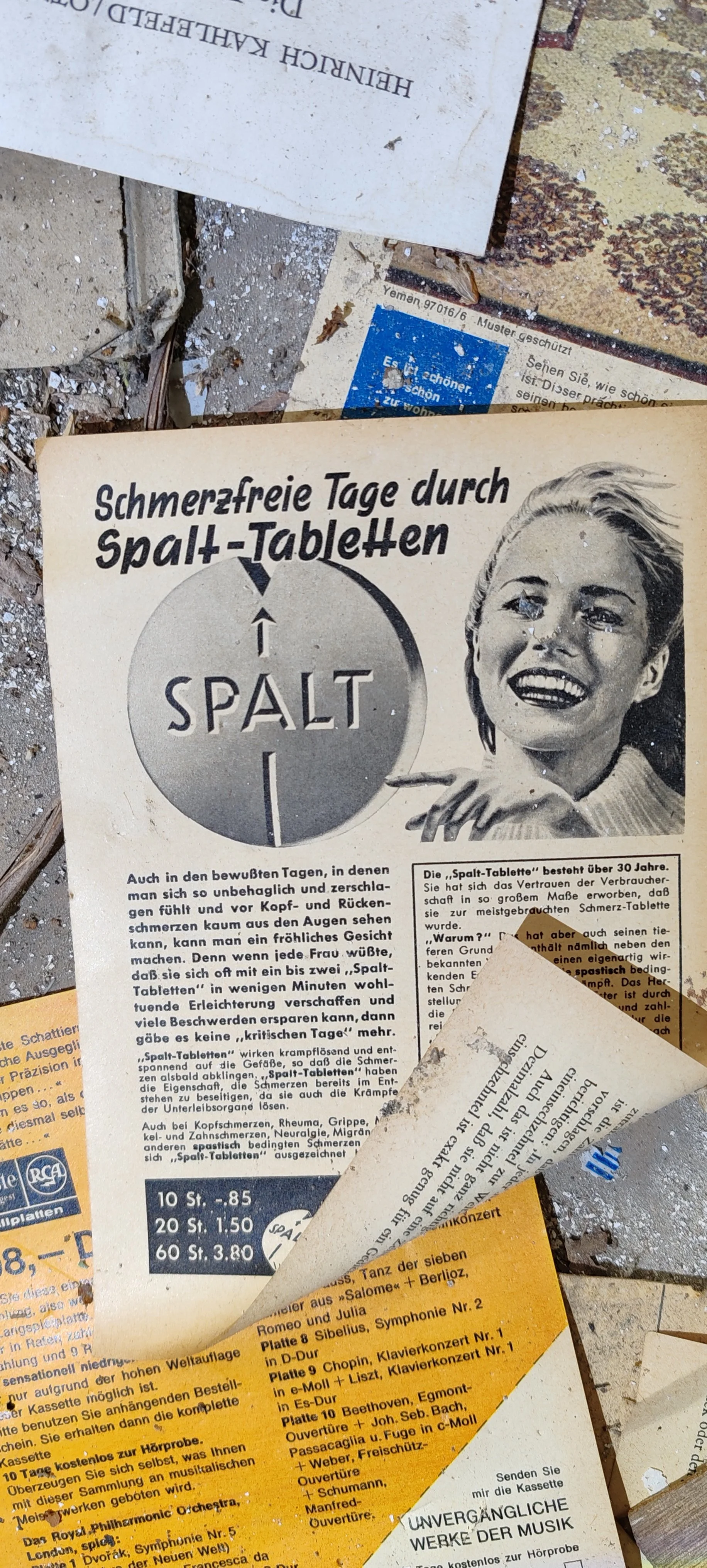 Alte, zerknitterte Werbeflyer für Spalt-Tabletten mit einem lachenden Frauenporträt, deutscher Text, Beinhalte, Preisangaben, teilweise abgeknickt und verstaubt.