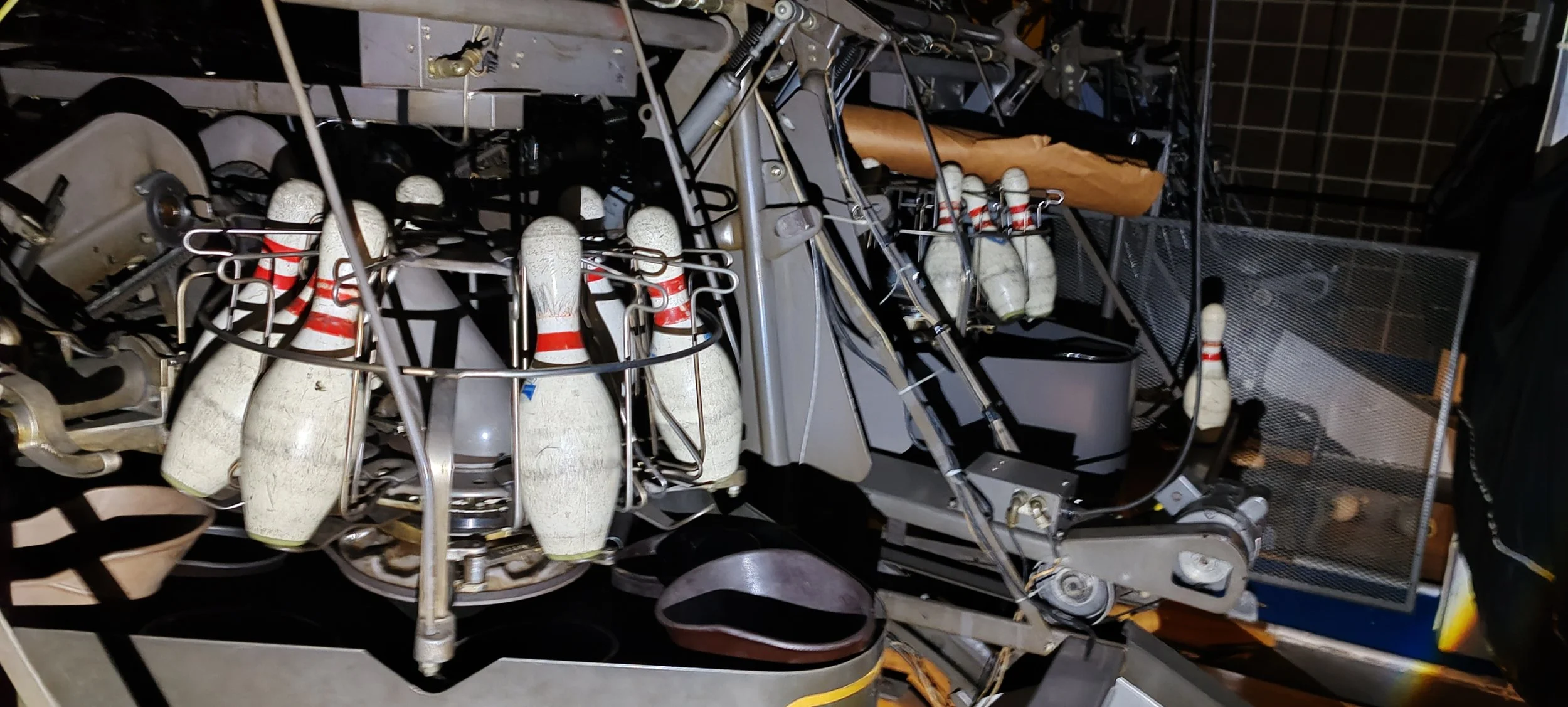 Nahaufnahme eines alten mechanischen Spiels mit weißen Bowlingkegeln mit roten Bändern, die auf einem floral dekorierten Kalkulator-ähnlichen Gerät stehen.