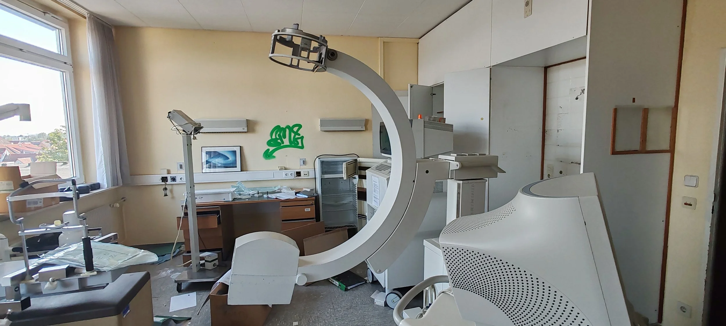 Ein verlassener Raum in einem Krankenhaus mit medizinischer Ausrüstung, einschließlich eines CT-Scanners, der unordentlich und verlassen wirkt.