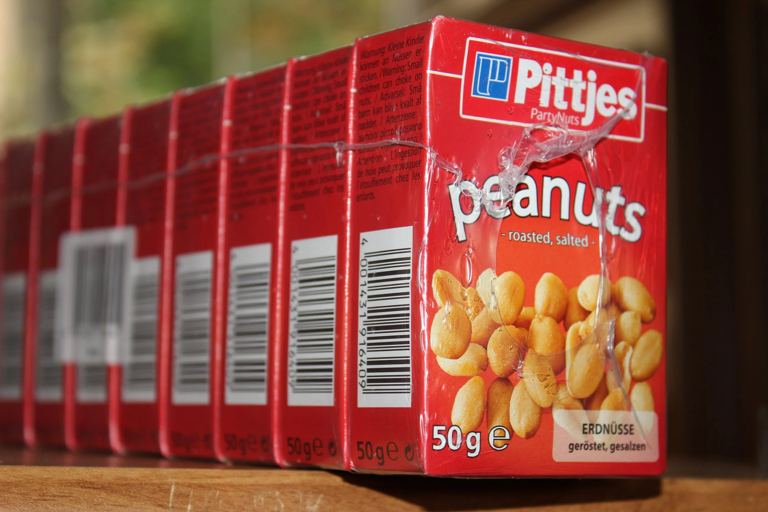 Mehrere rote Verpackungen Pritties Erdnüsse, geröstet und gesalzen, auf einem Holzregal, Nahaufnahme.