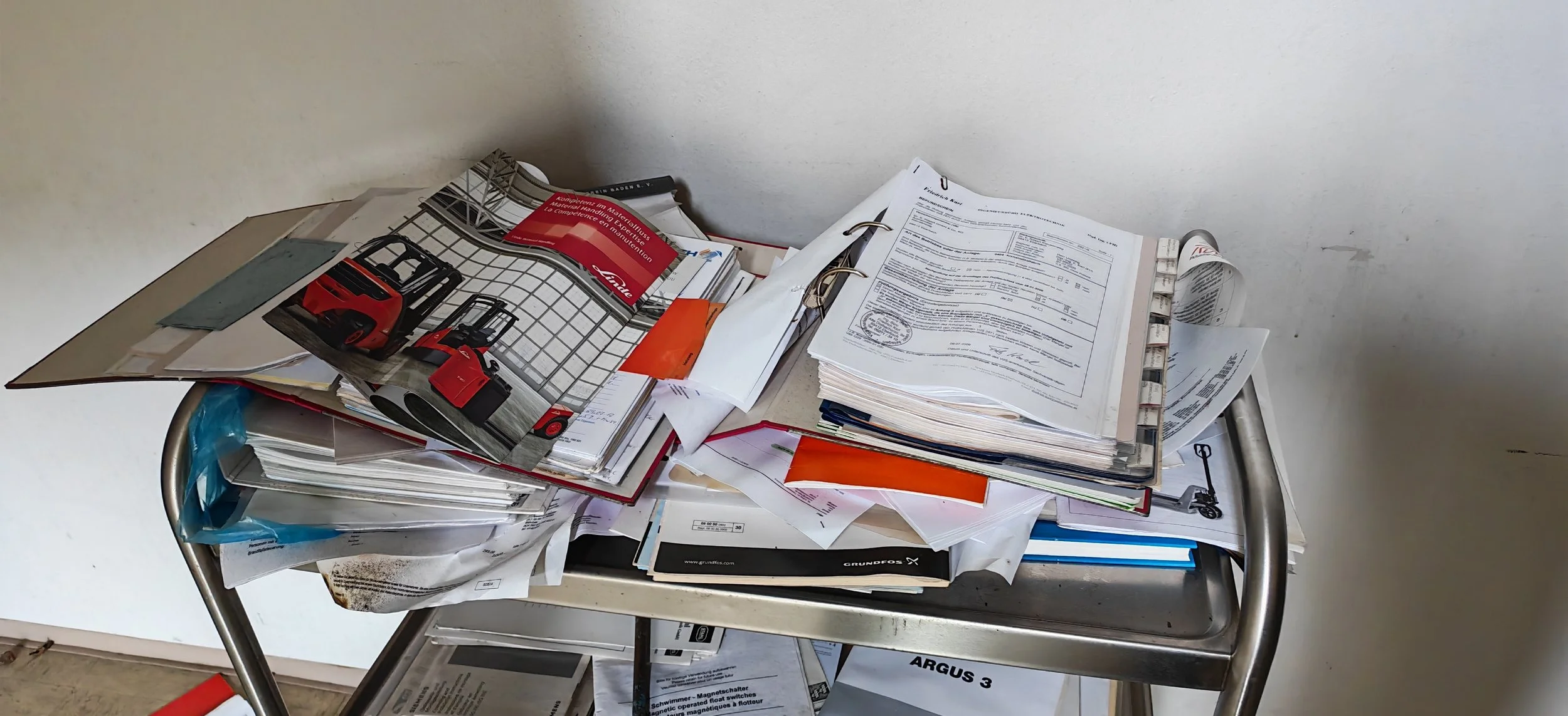 Ein Tisch voller durcheinanderliegender Dokumente, Papierstapel und Zeitschriften.