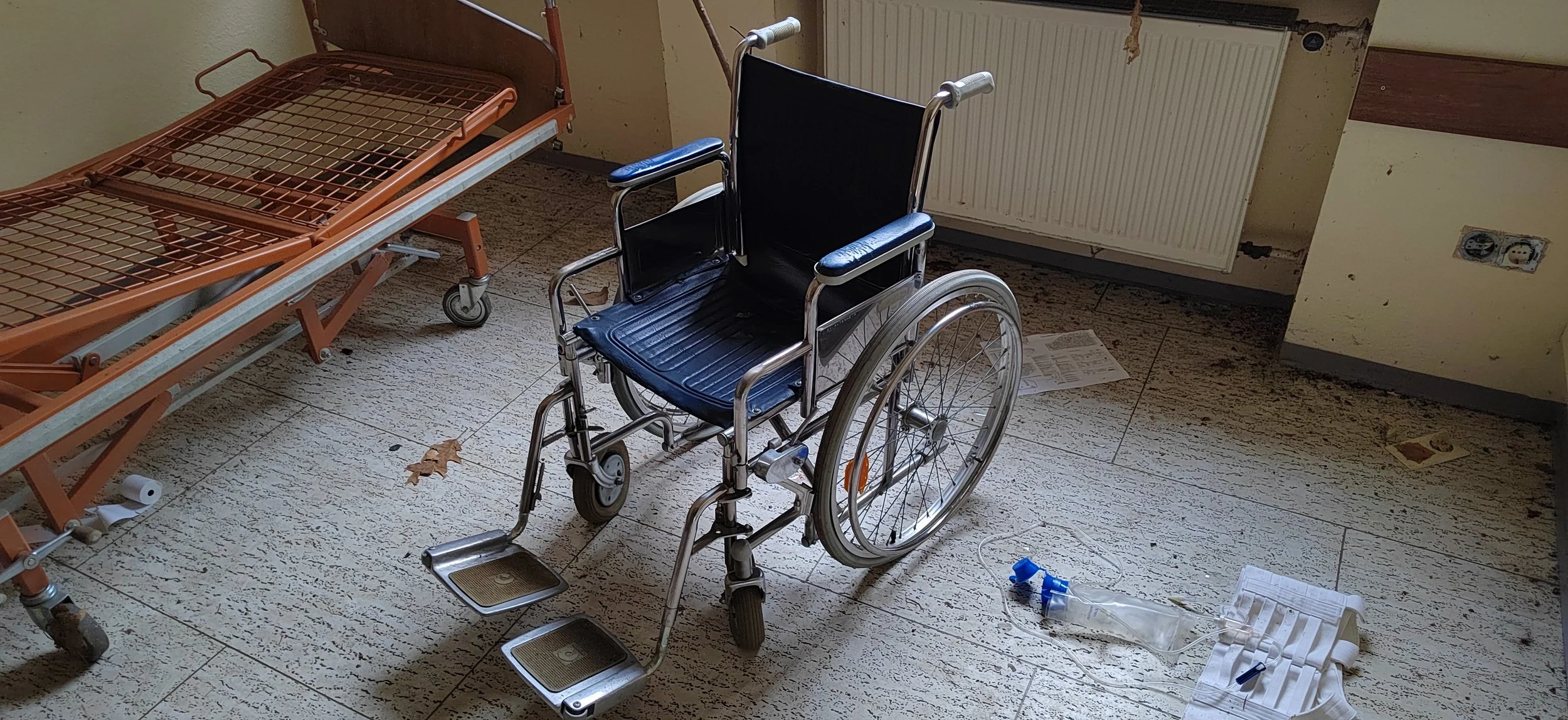 Ein Krankenhaustelefon mit Rollstuhl und einem leeren Bett im Krankenhauszimmer.