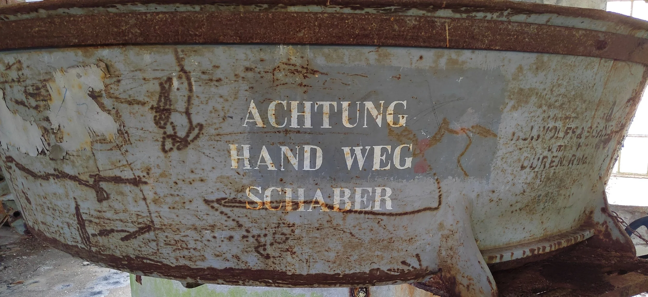 Rostiges Metallboot mit warnender Aufschrift in deutscher Sprache.