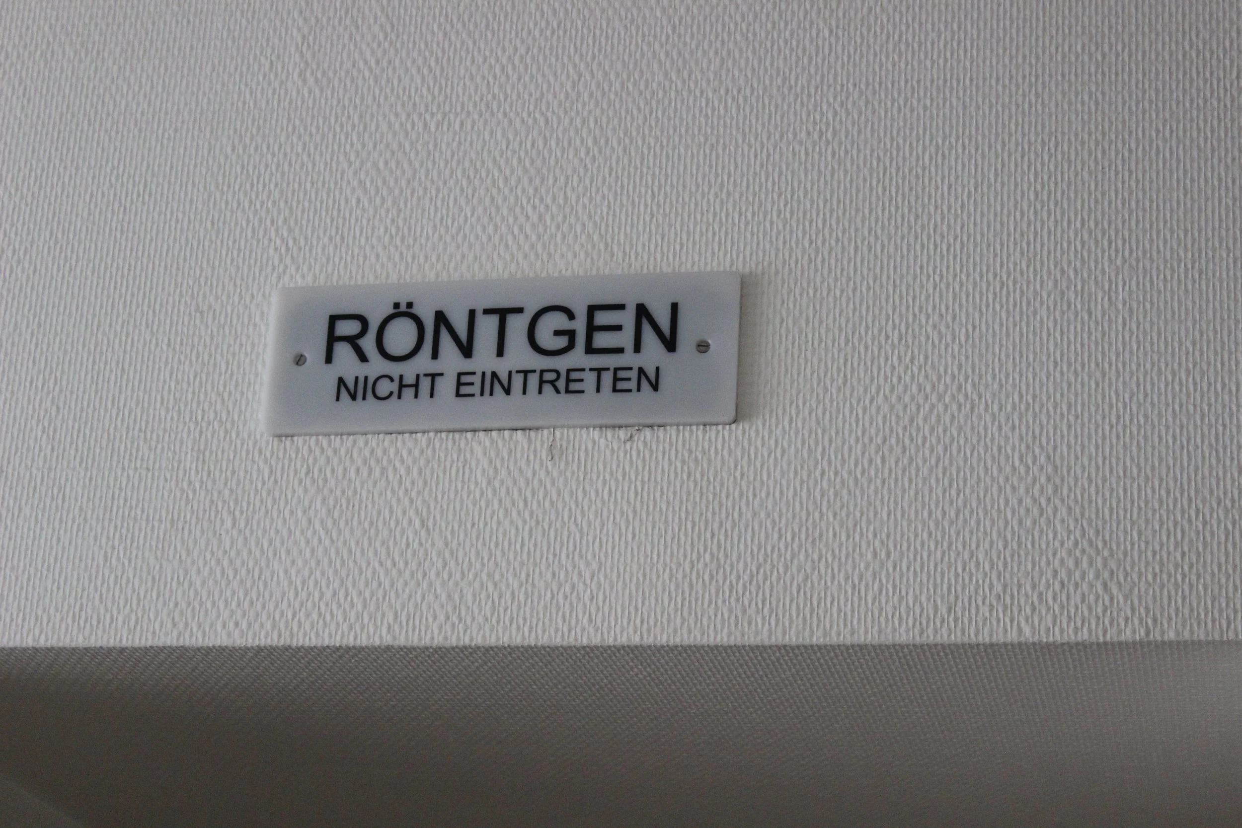 Hinweisschild an der Wand, das auf eine Röntgenanlage hindeutet, mit der Anweisung 'Nicht betreten'.