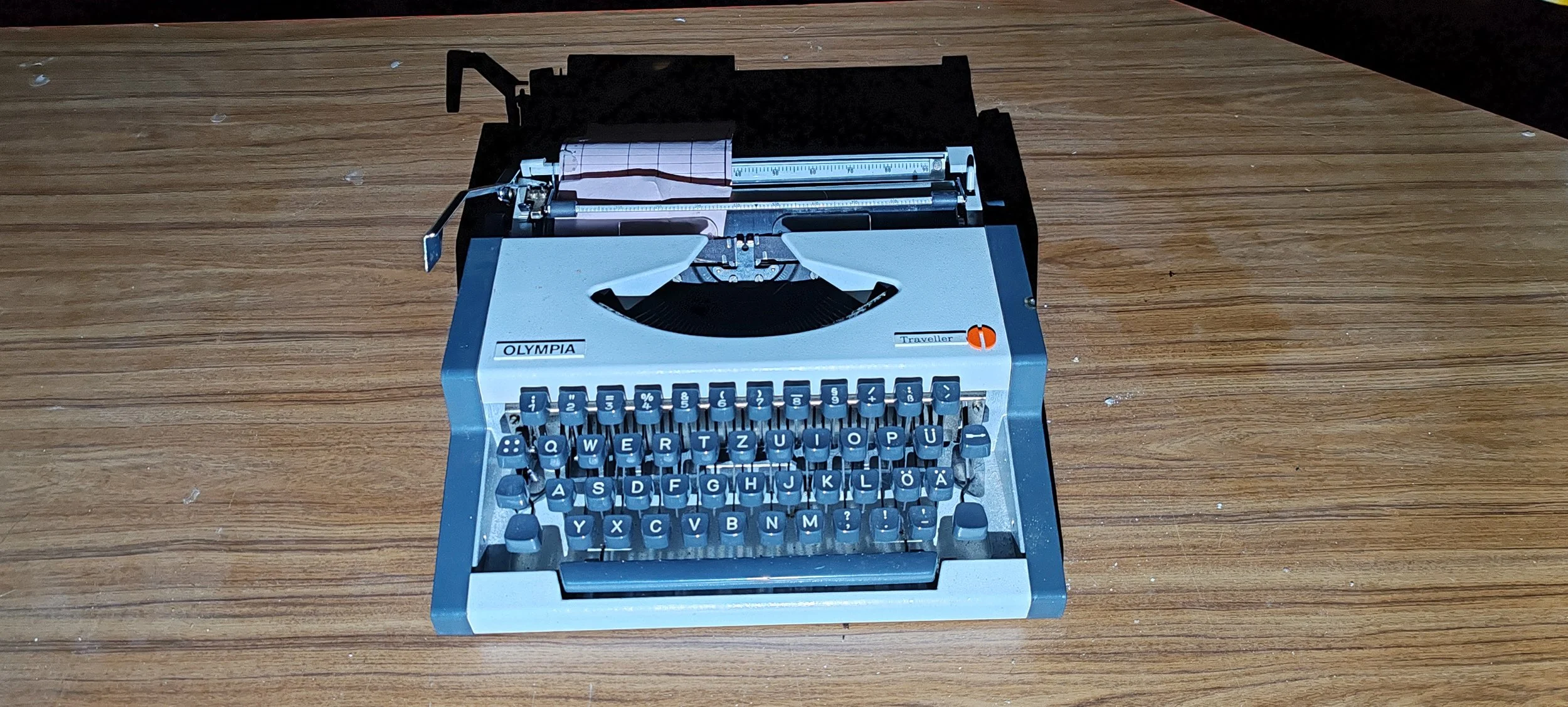 Eine alte blaue Schreibmaschine auf einem Holztisch.