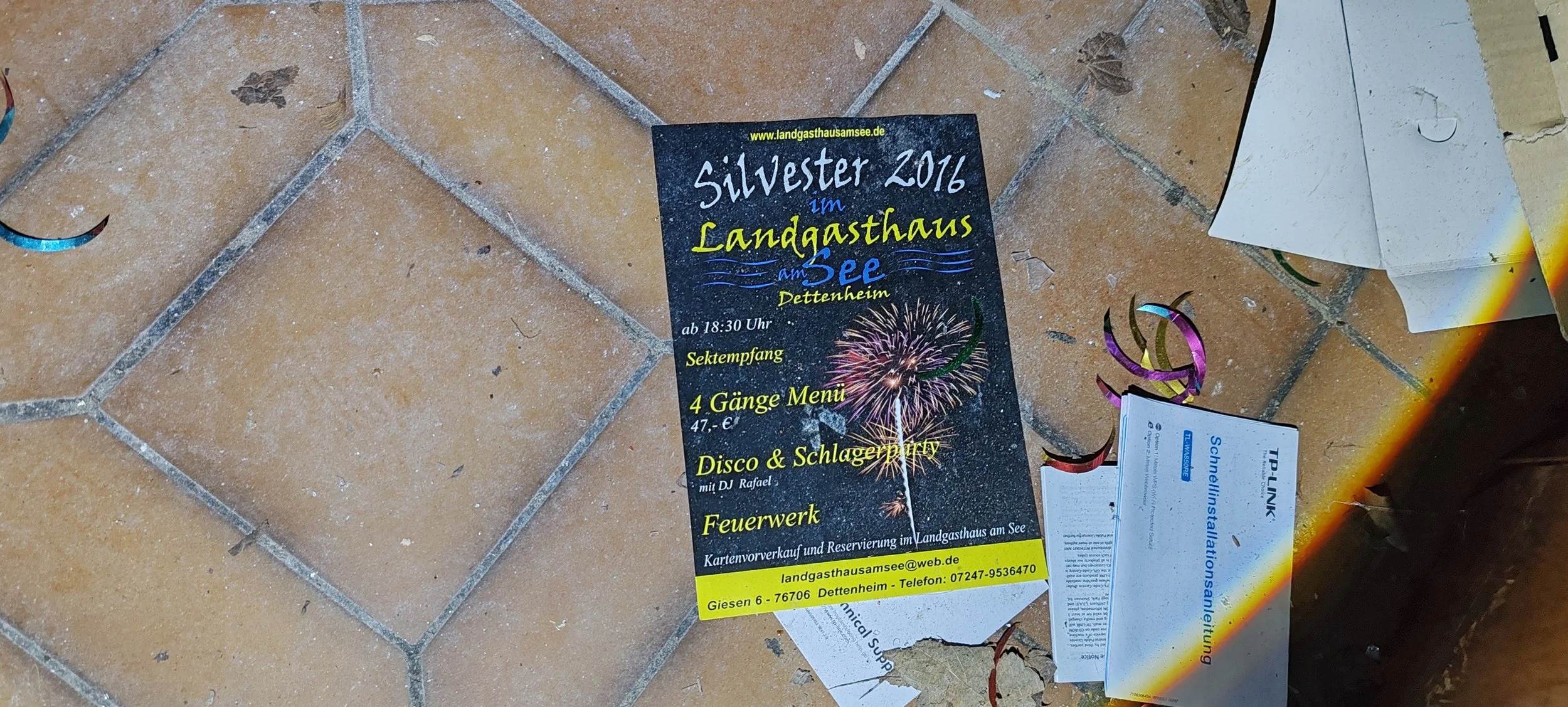 Veranstaltungsflyer für Silvester 2016 im Landgasthaus am See in Dettenheim, mit Feuerwerk, Sekt Empfang, Menü, Disco, und Balkon. Auf dem Boden liegen ebenfalls Tickets und Dekorationsmaterial.