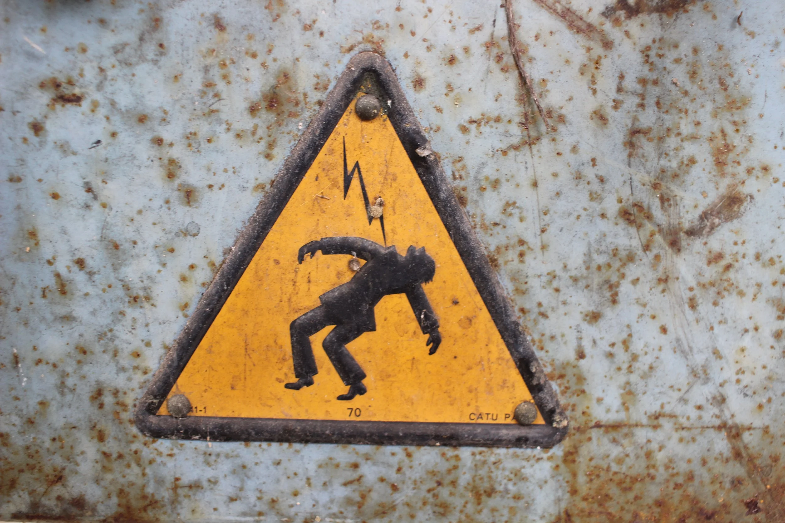 Warnschild mit einem prähistorischen Menschen, der vor einem Blitz flieht, auf einem rostigen Metall surface.