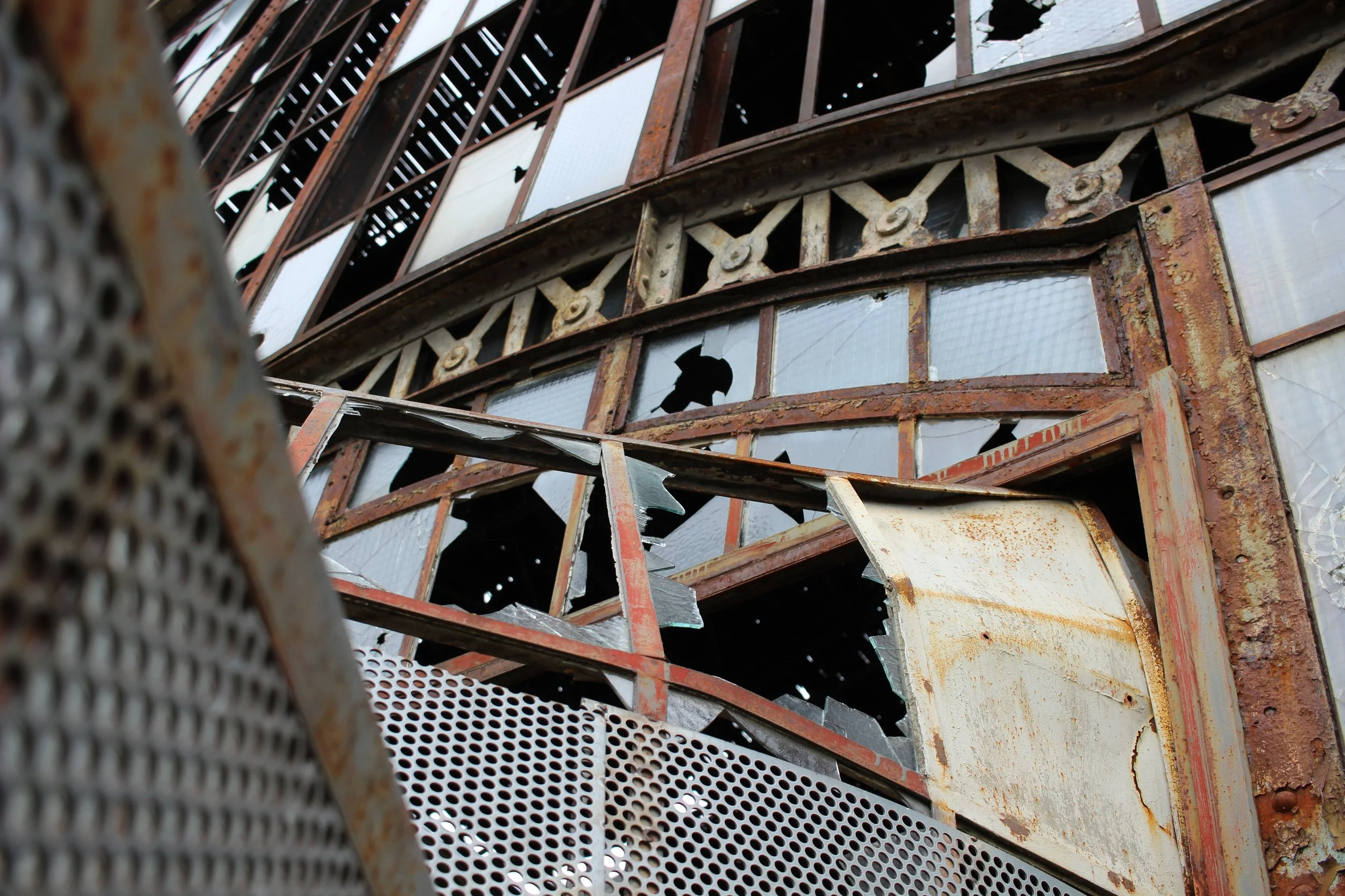 Ein verrostetes, beschädigtes Gebäude mit zerbrochenen Fenstern und durchhängendem, beschädigtem Metallgeländer.