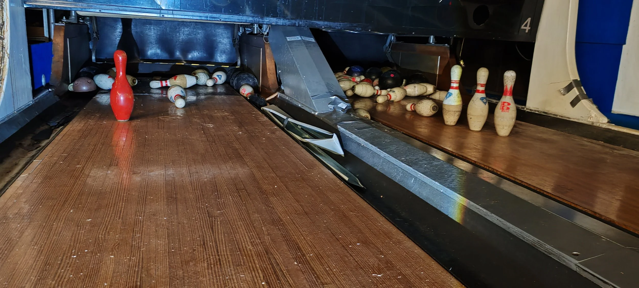 Bowlingbahn mit umgefallenen Pins und abgerissener Kugel.