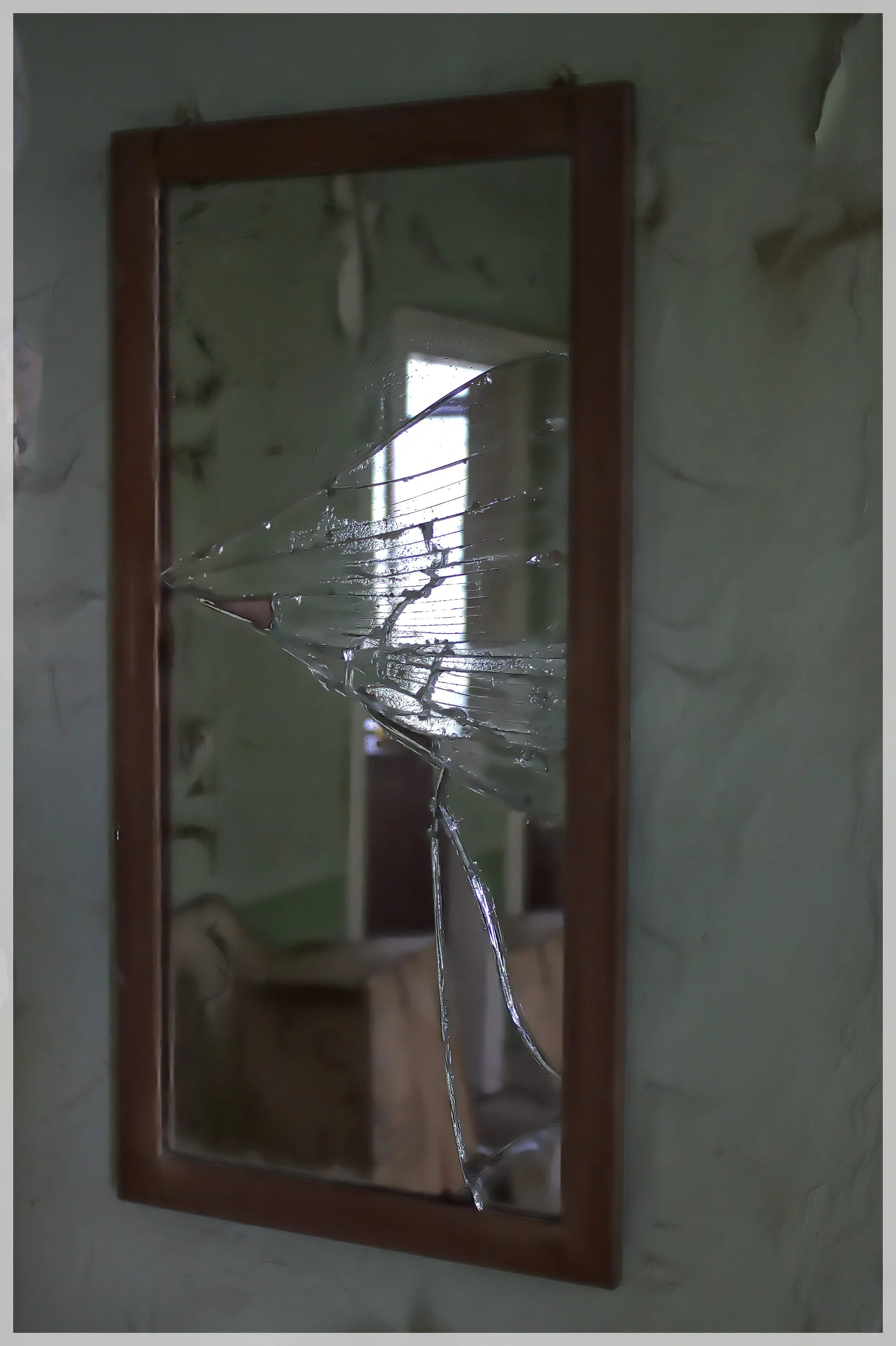 Ein zerbrochener Spiegel mit zersplittertem Glas, das an einer Wand hängt