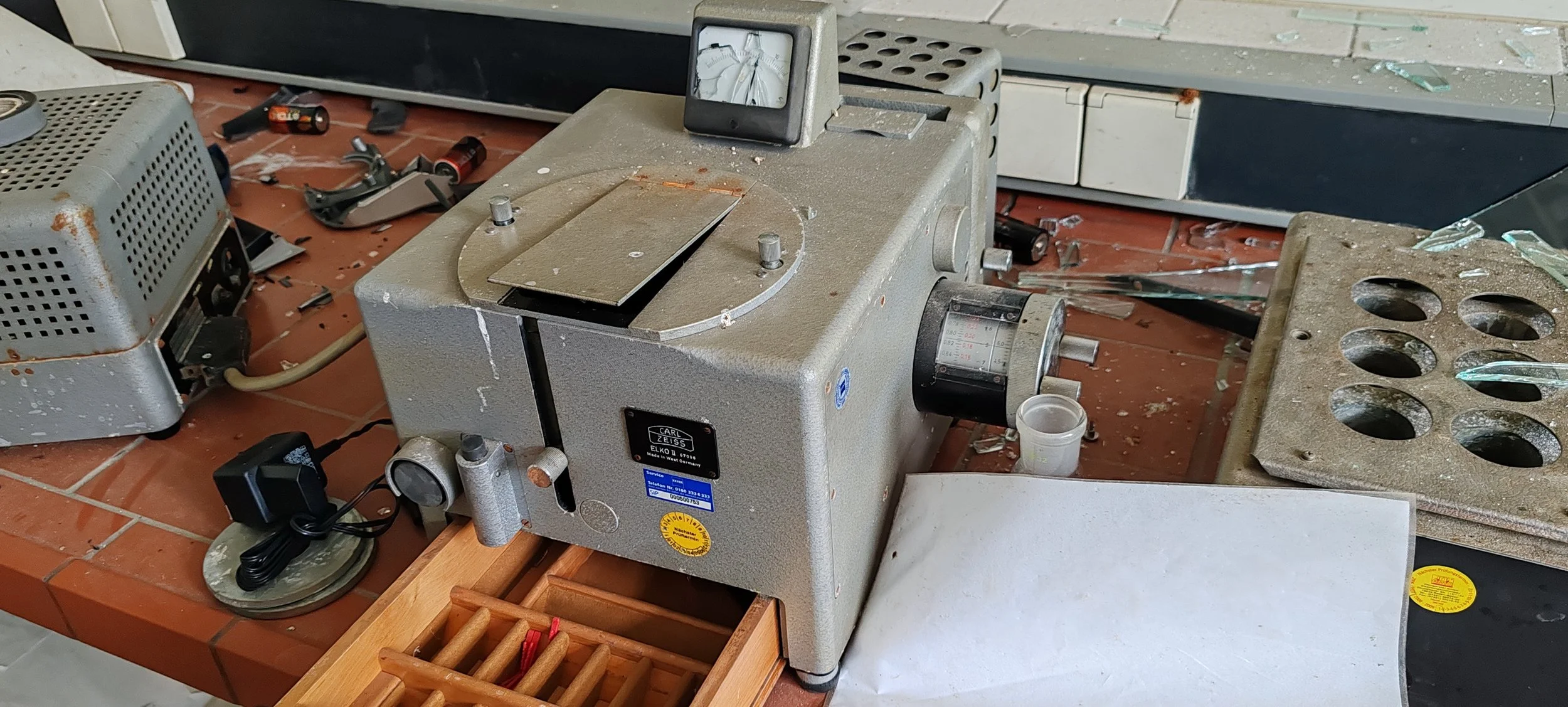 Laborgerät auf einem Tisch in einem Labor, umgeben von Scherben, Werkzeugen und anderen Gegenständen.
