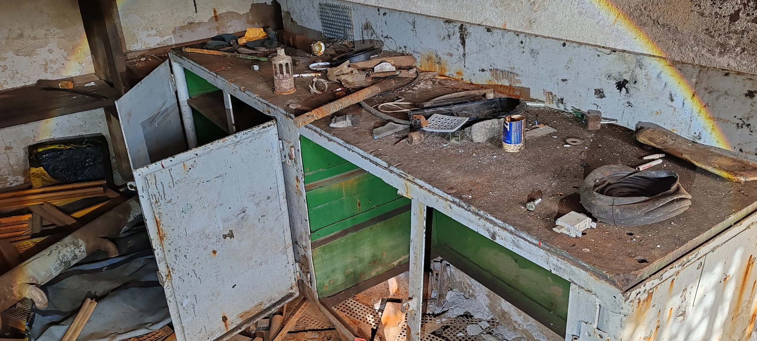 Verrosteter und schmutziger Werkbank mit Werkzeugen, Schrauben und Staub in einer alten Werkstatt.