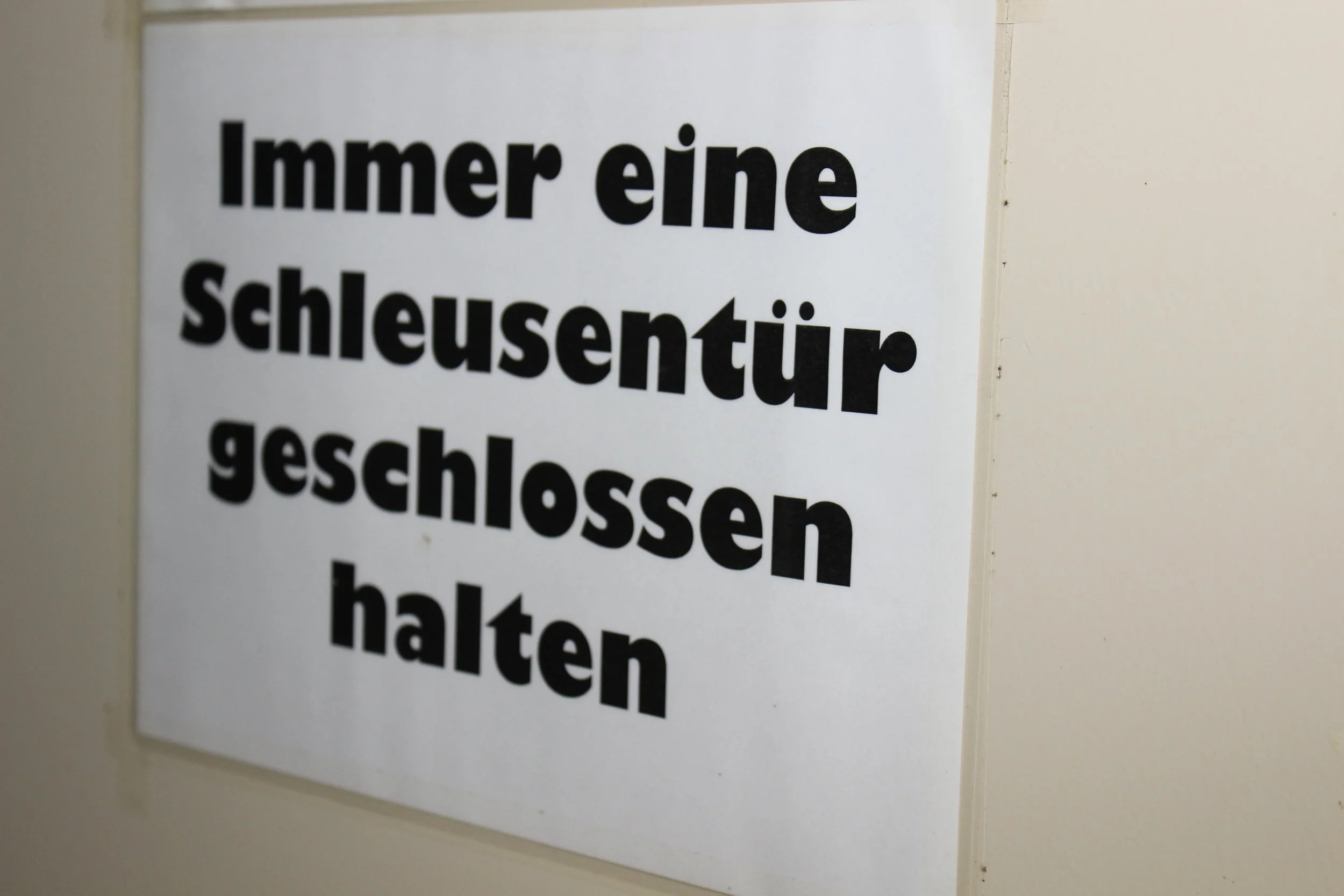 Hinweisschild auf Deutsch, also 'Immer eine Schleusentür geschlossen halten'.