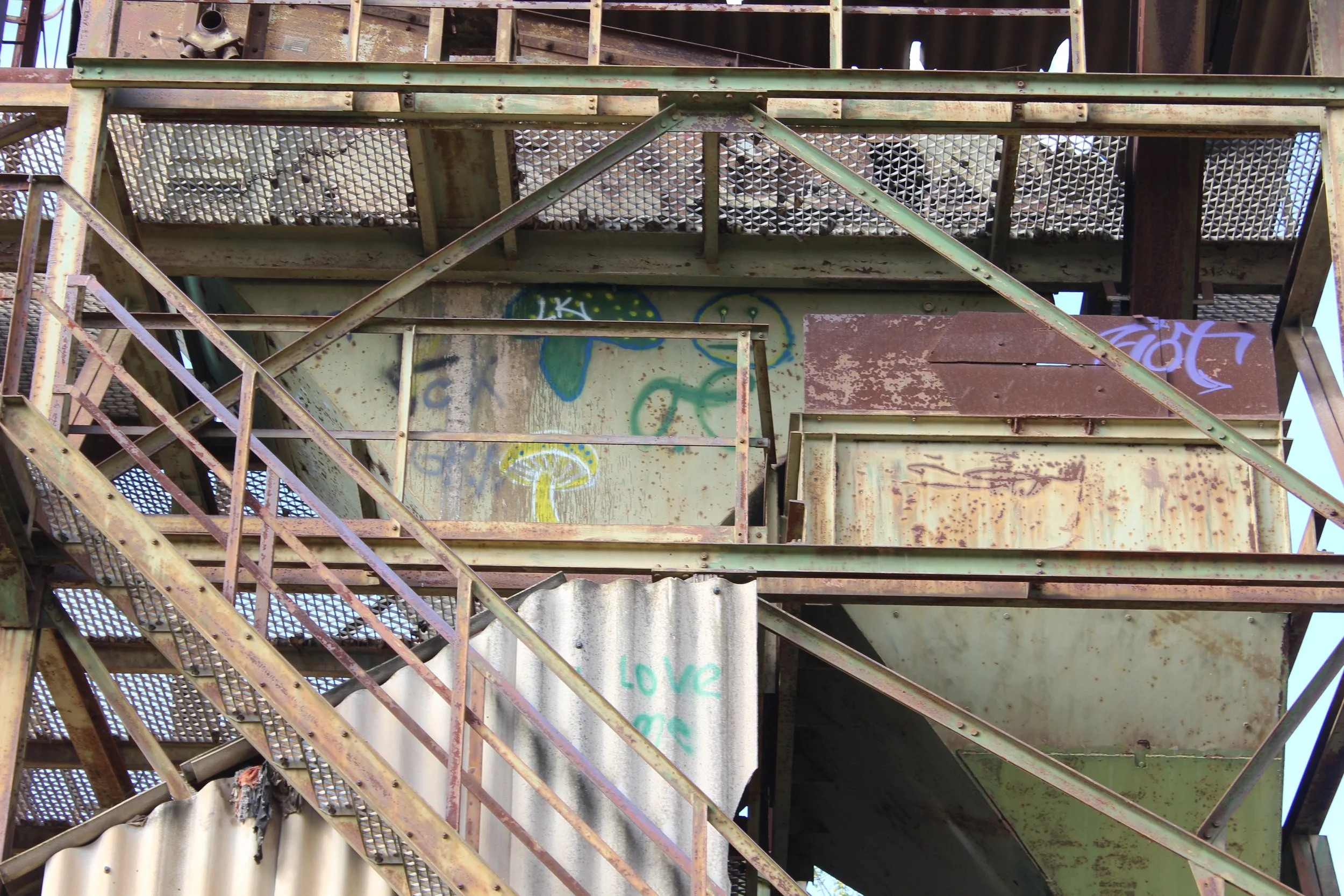 Stahltreppe und Plattform eines alten, verrosteten Industriegebäudes mit Graffiti