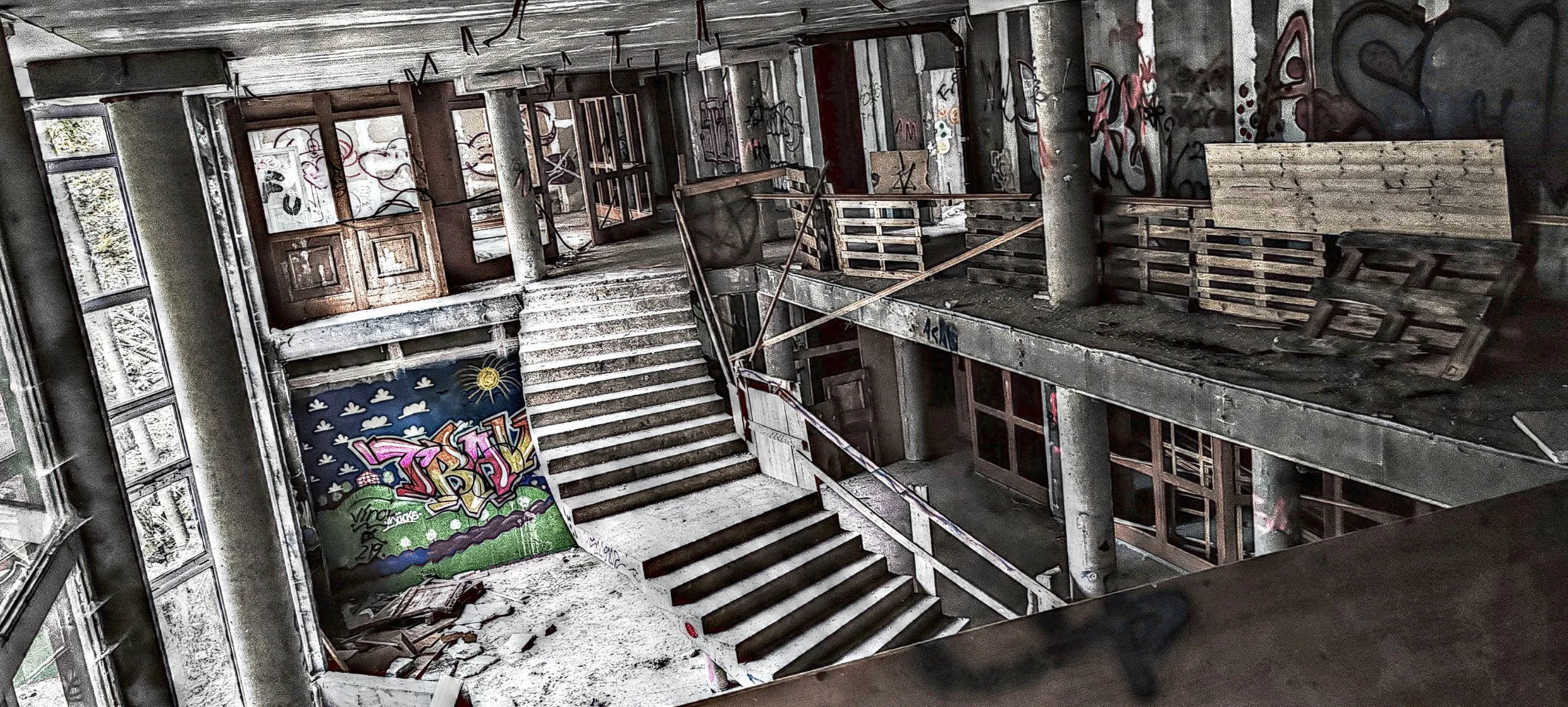 Ein verfallenes, graffiti-übersätes Gebäude mit halb zerstörten Treppen und zerbrochenen Fenstern.
