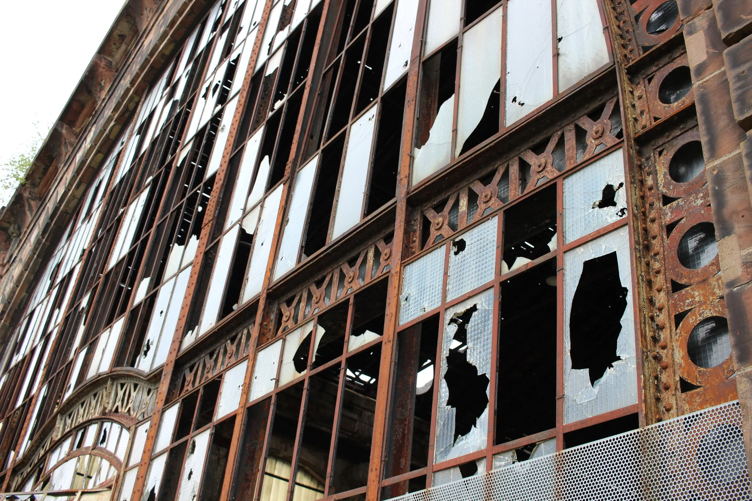 Ein verfallenes Gebäude mit zerbrochenem Glas und rostigem Metallgitter an den Fenstern.