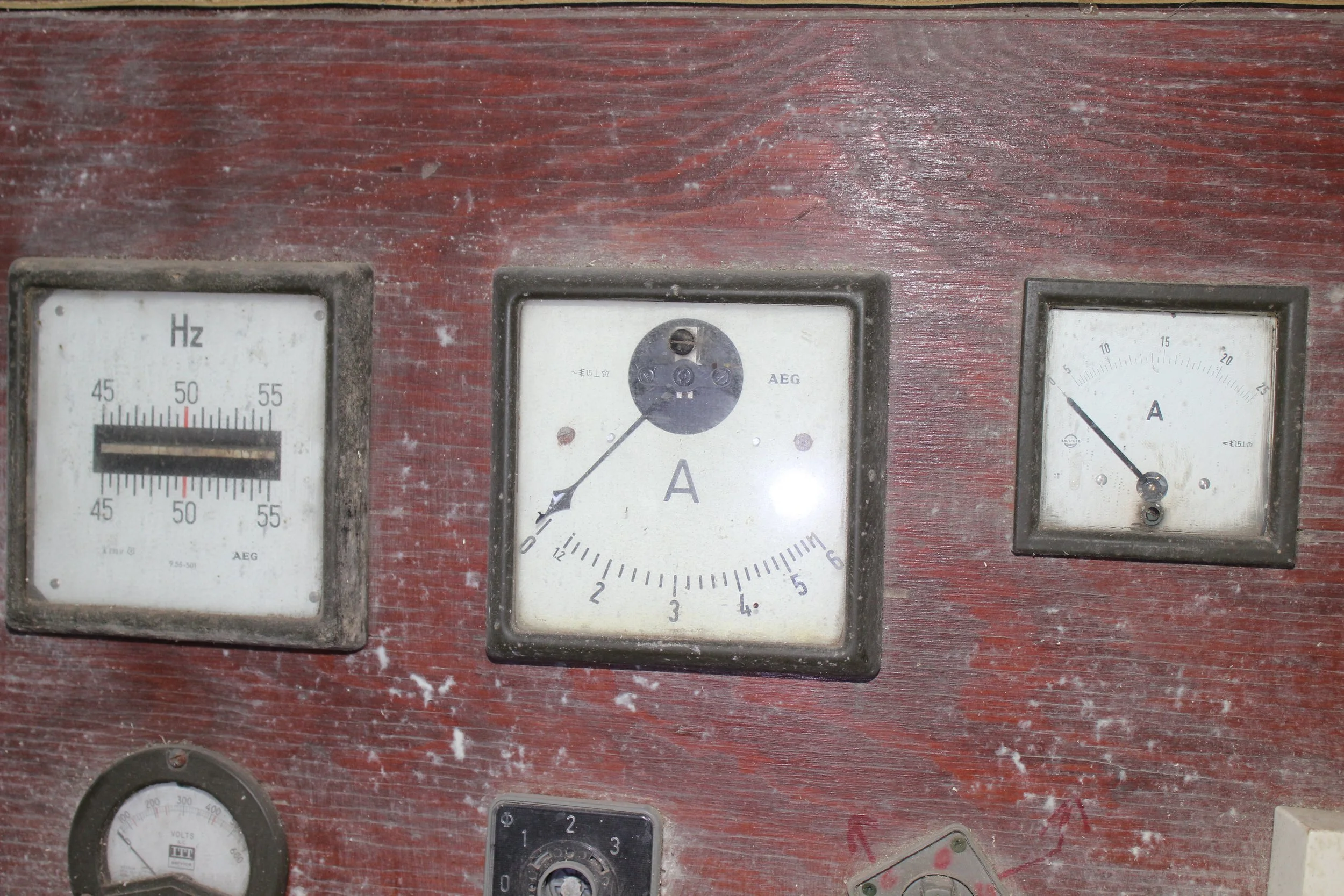 Alte Messgeräte an einer Holzoberfläche, darunter ein Amperemeter, ein Voltmeter und ein Amperemeter