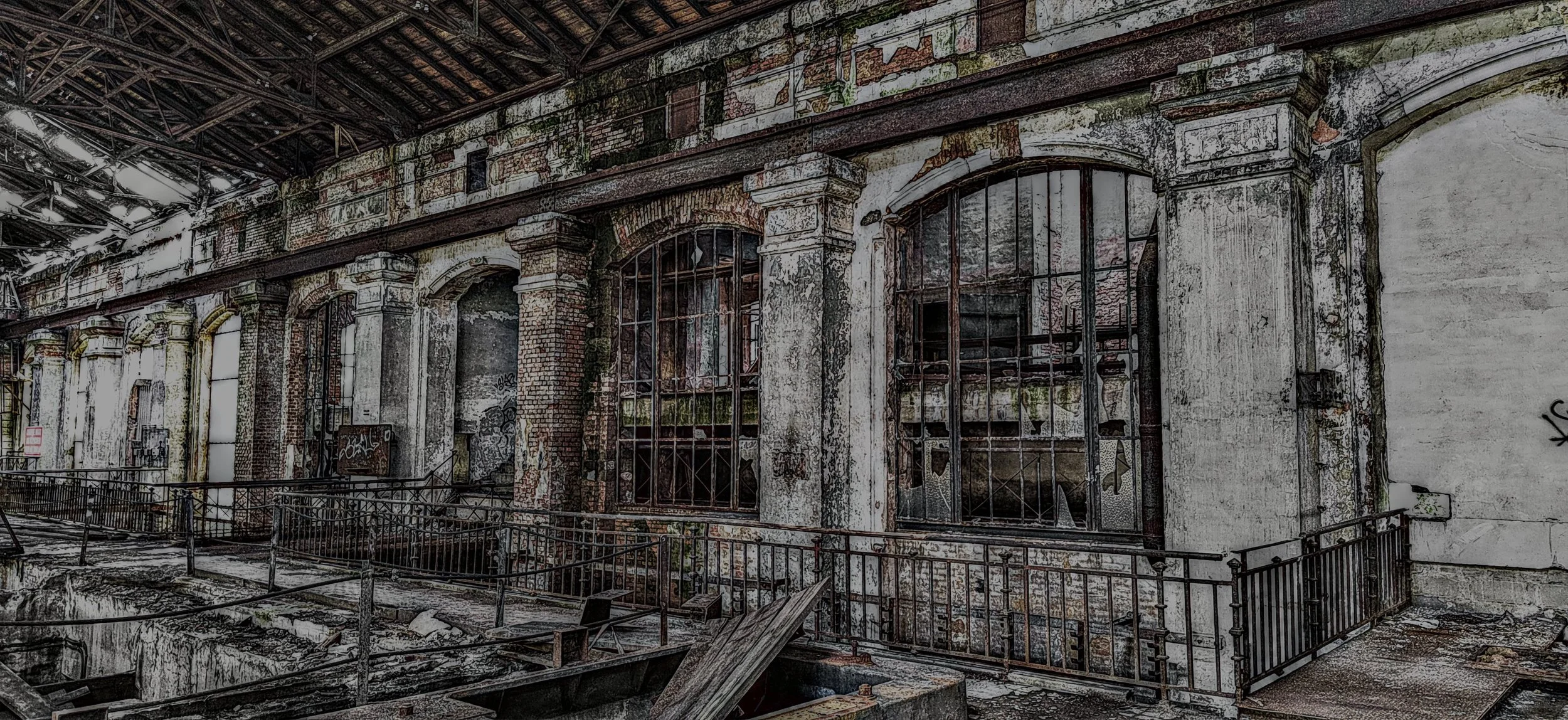 Verlassene, verfallene Fabrikhalle mit zerbrochenen Fenstern, Rost und Graffiti an den Wänden.