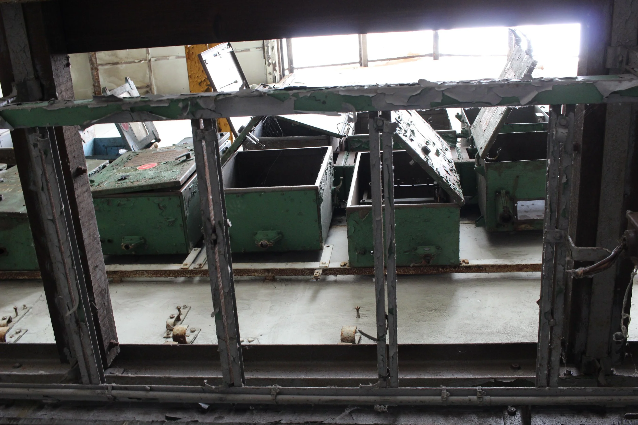 Verlassene, alte industrielle Maschine in einem Fensterrahmen, mit Rost und Kabeln, in einem Raum mit natürlichem Licht.